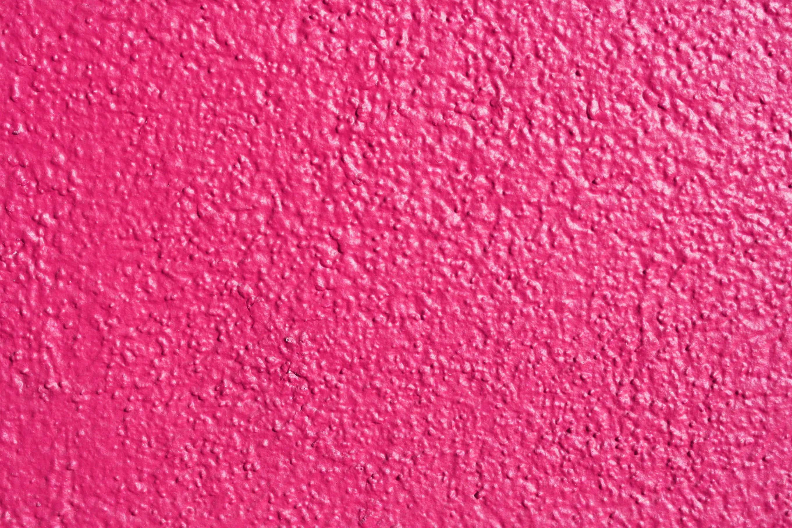 Pink Color 桌布 壁紙 — 在均勻照明下，帶有粗糙凹凸飾面的鮮豔粉紅色紋理牆面。