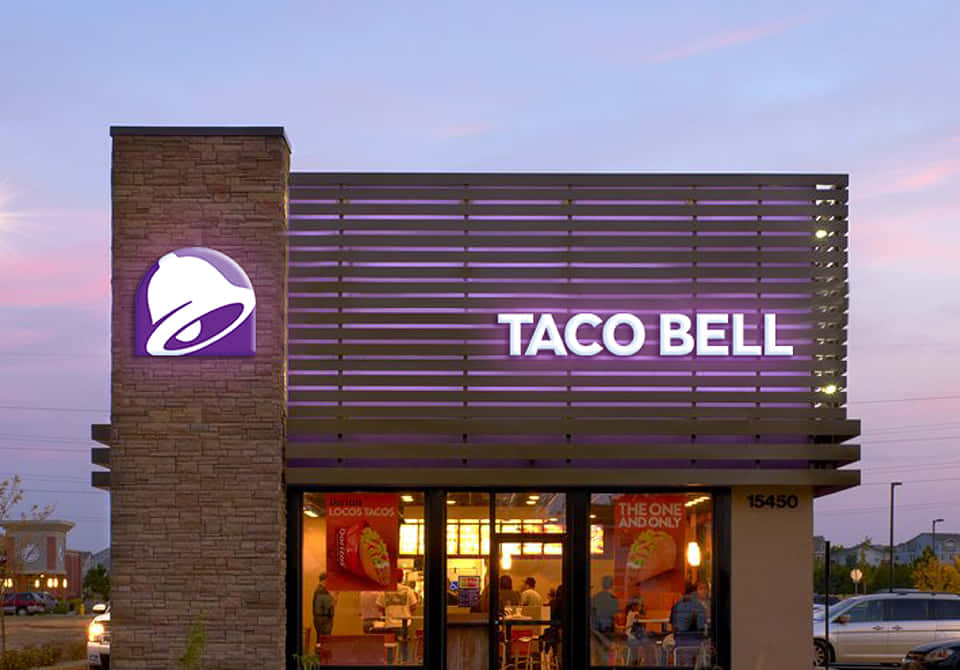 黃昏時分Taco Bell餐廳外觀，帶有發光招牌和溫暖的室內燈光。