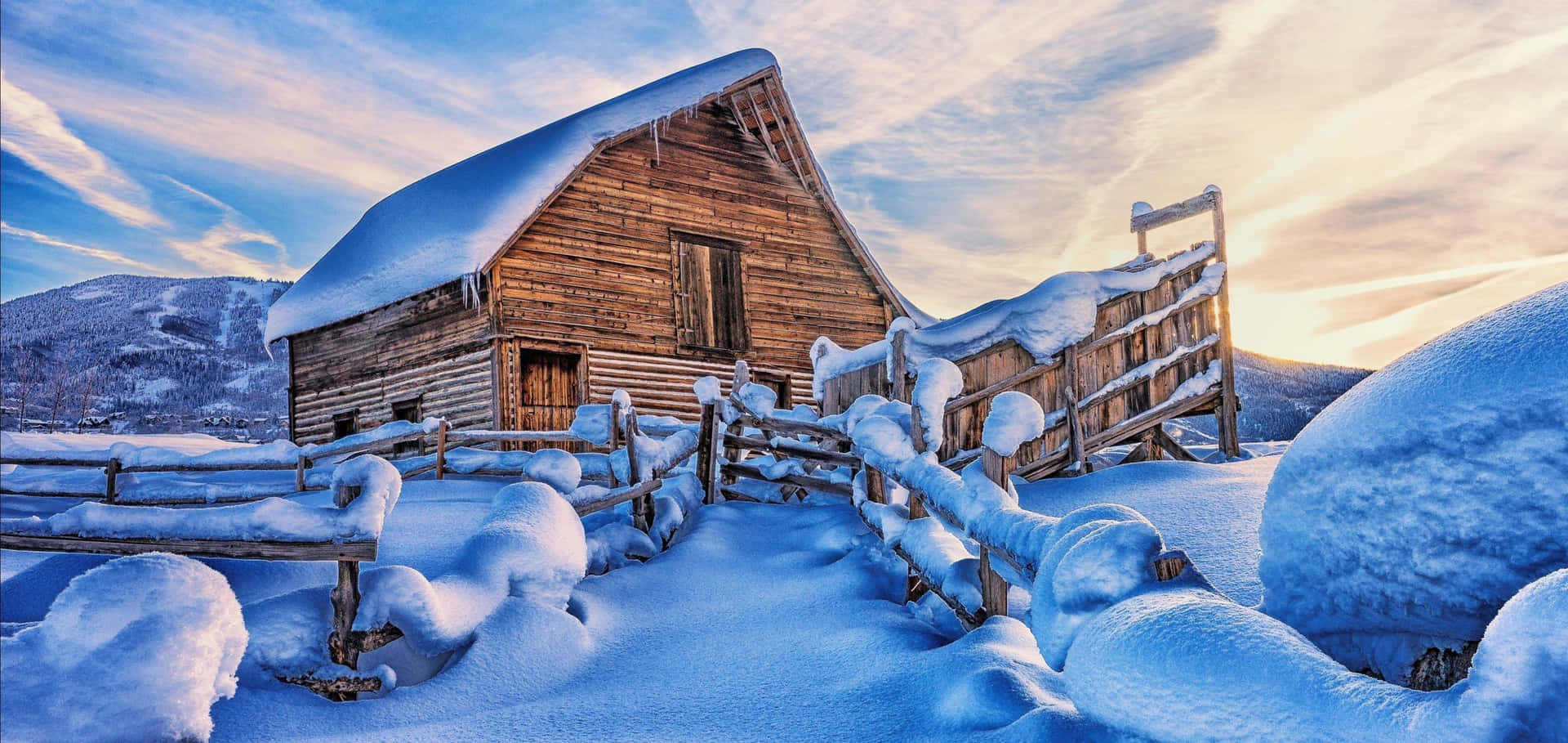 被雪覆蓋的木屋與籬笆，冬季日落景觀