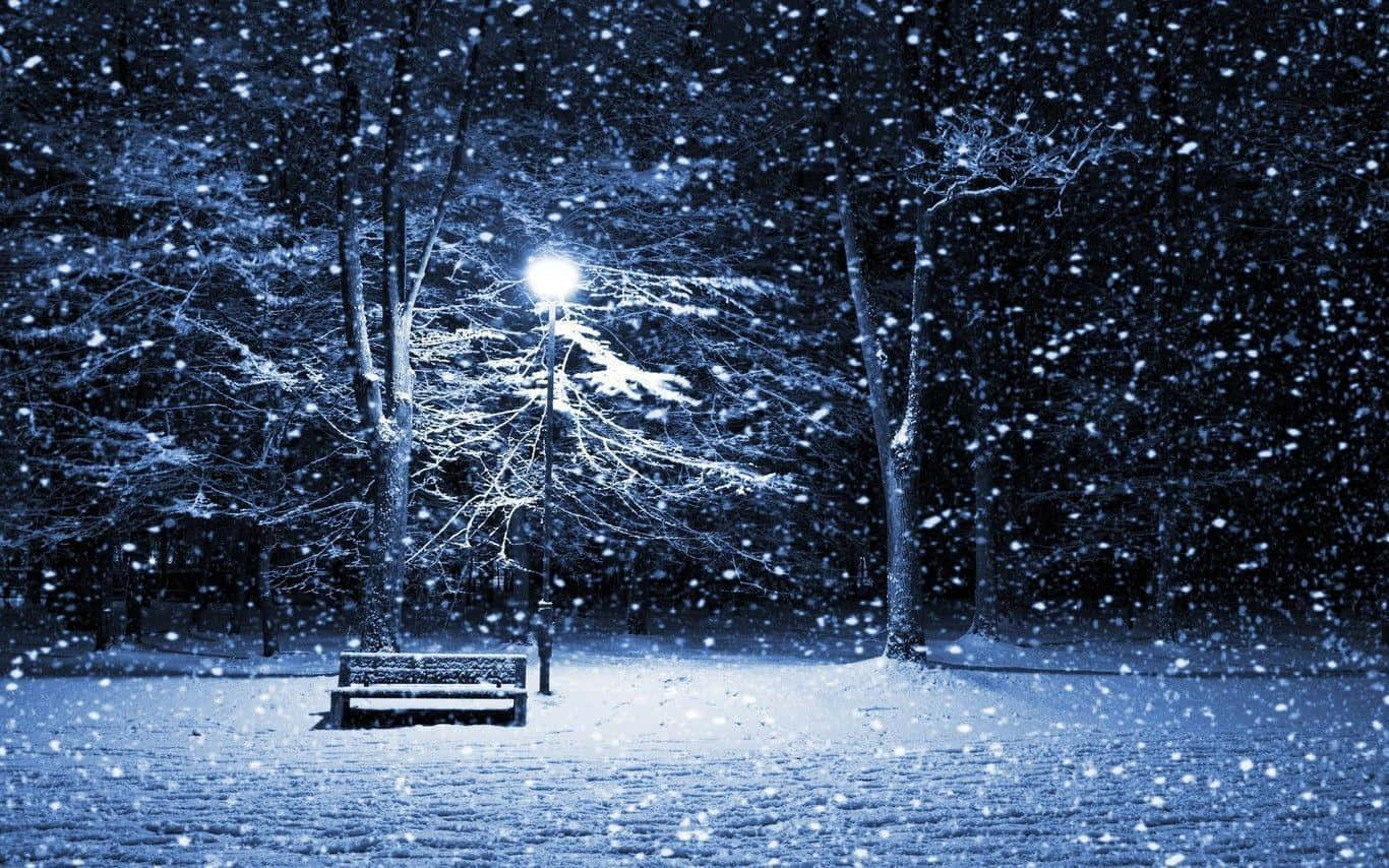 Snowstorm 桌布 壁紙 — 在寧靜的冬夜公園裡，一張孤獨的雪覆長椅在街燈下閃耀，大雪紛飛。