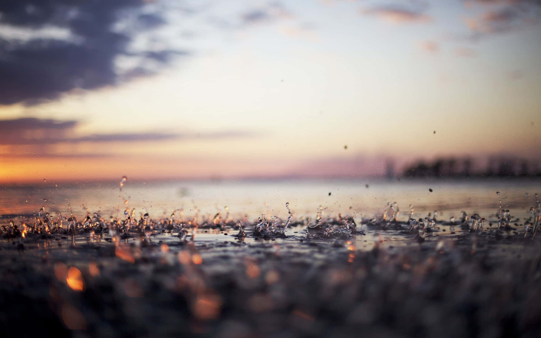 在寬屏中欣賞大自然之美 壁紙 — 雨滴在濕地上生動地飛濺，柔和的夕陽將天空染成溫暖的橙色和紫色。