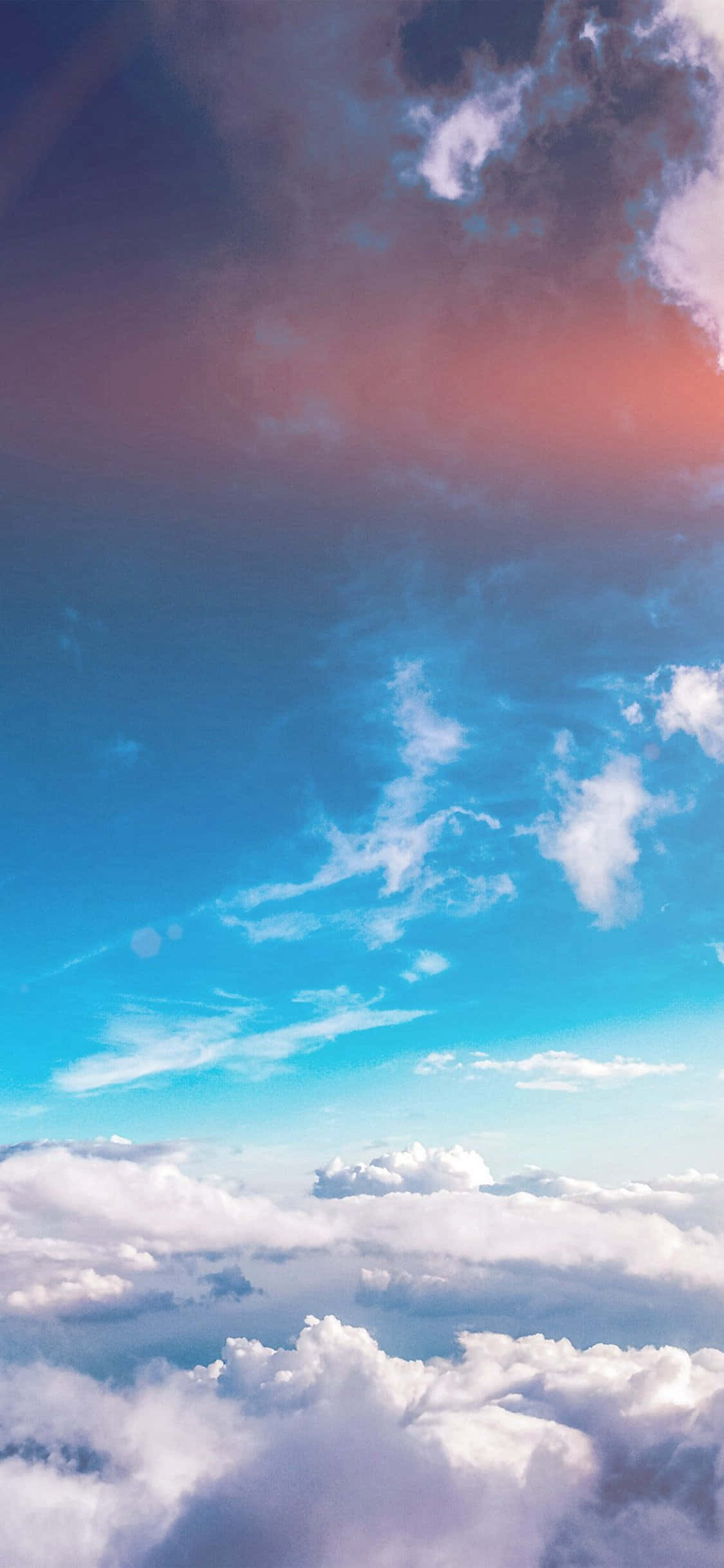 Cloud Aesthetic 桌布 壁紙 — 在帶有粉紅和紫色日落色調的鮮豔藍天下，翱翔於蓬鬆白雲之上的航拍視角。