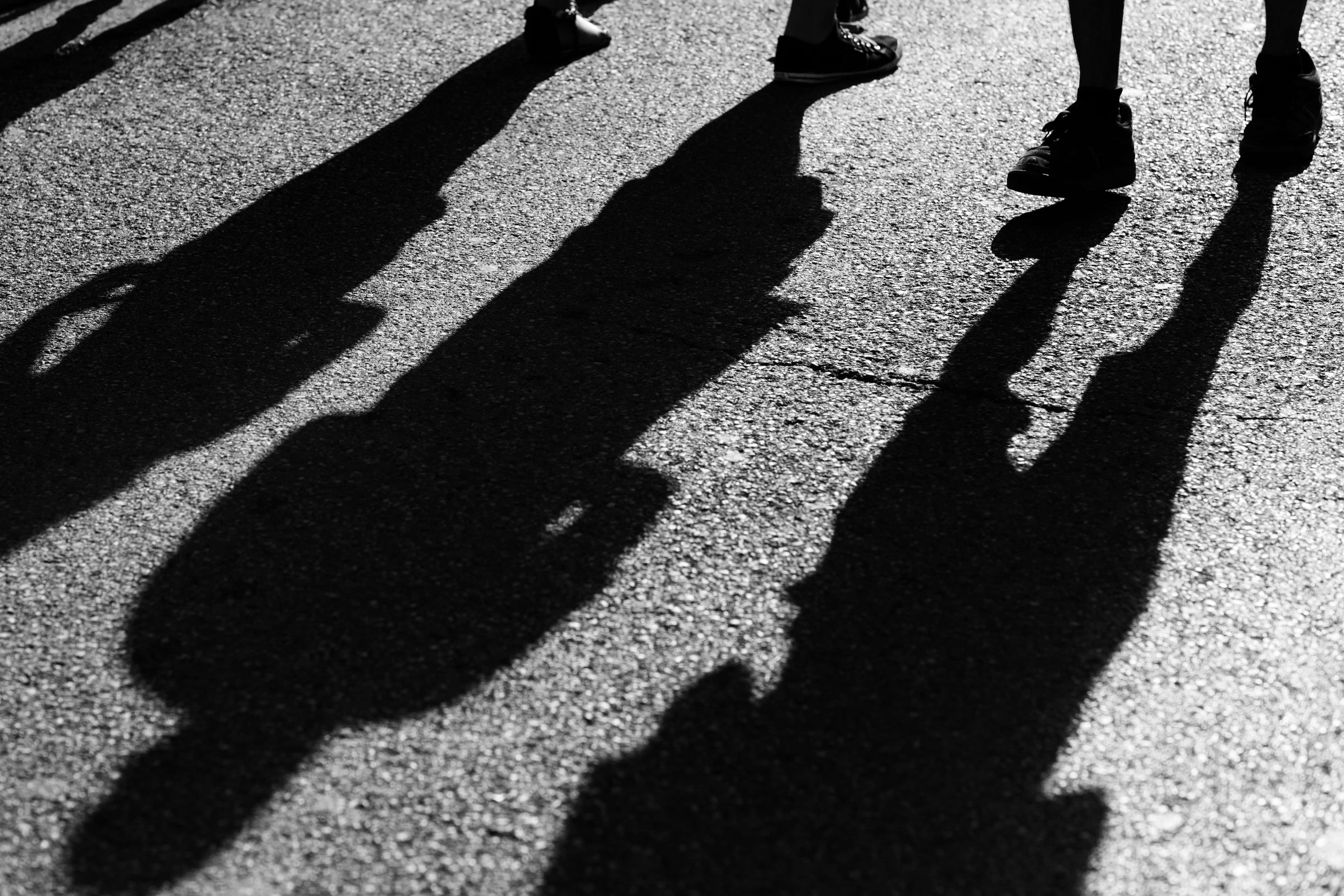 shadow 桌布 壁紙 — 在強烈陽光下，行人戲劇性的黑白影子伸展在紋理人行道上。