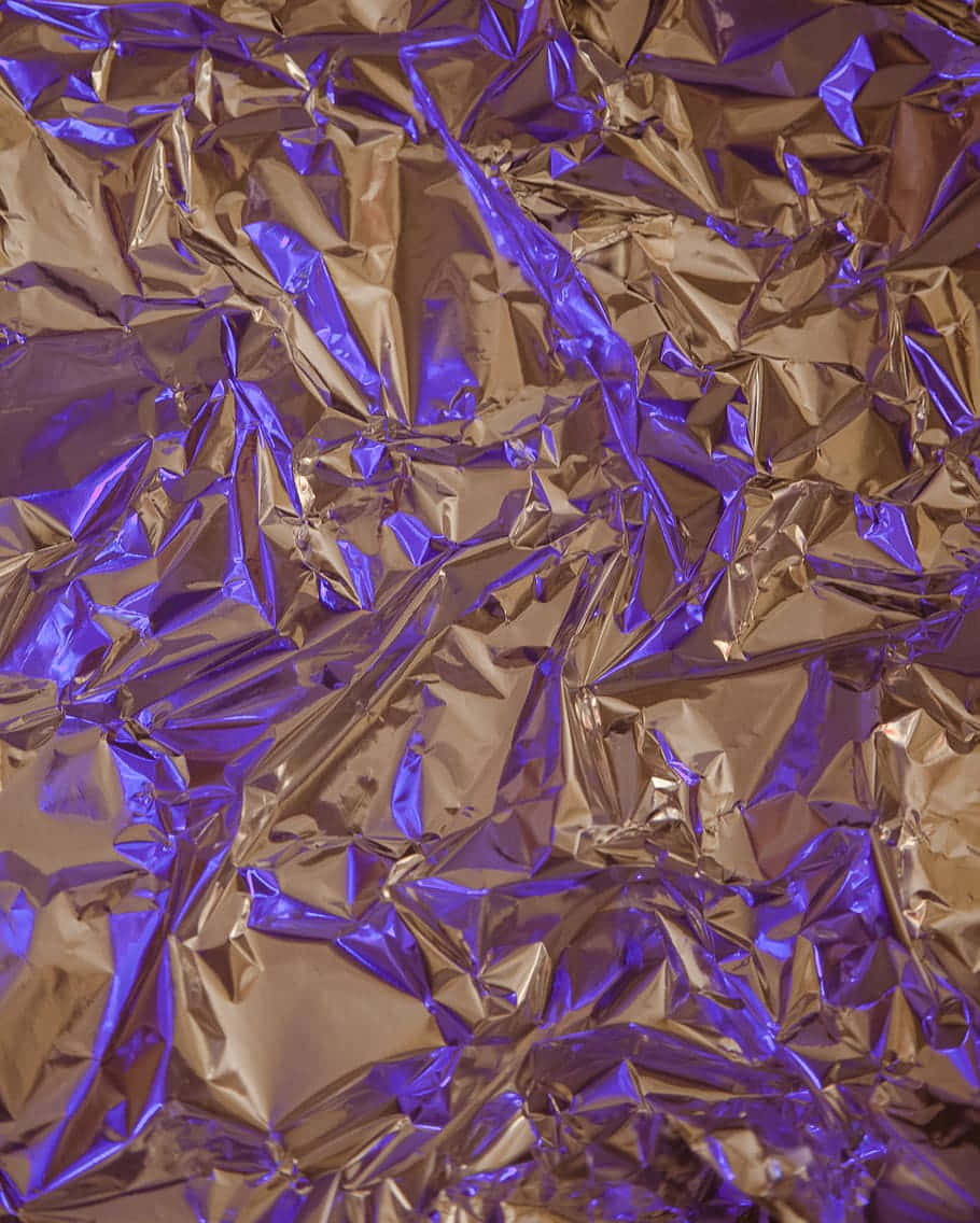 Foil 桌布 壁紙 — 在戲劇性燈光下，帶有金色亮點和深紫色反射的皺褶金屬箔。