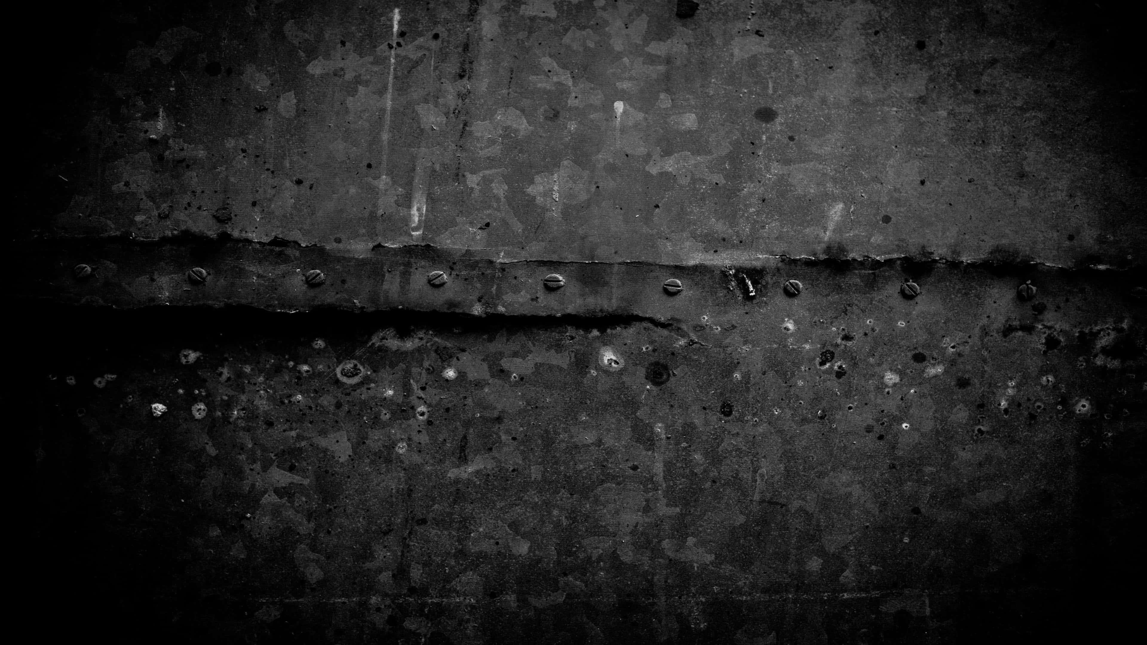 Dark Grunge 桌布 壁紙 — 在戲劇性燈光下，風化金屬帶有鉚釘和鏽跡的粗糙單色特寫。