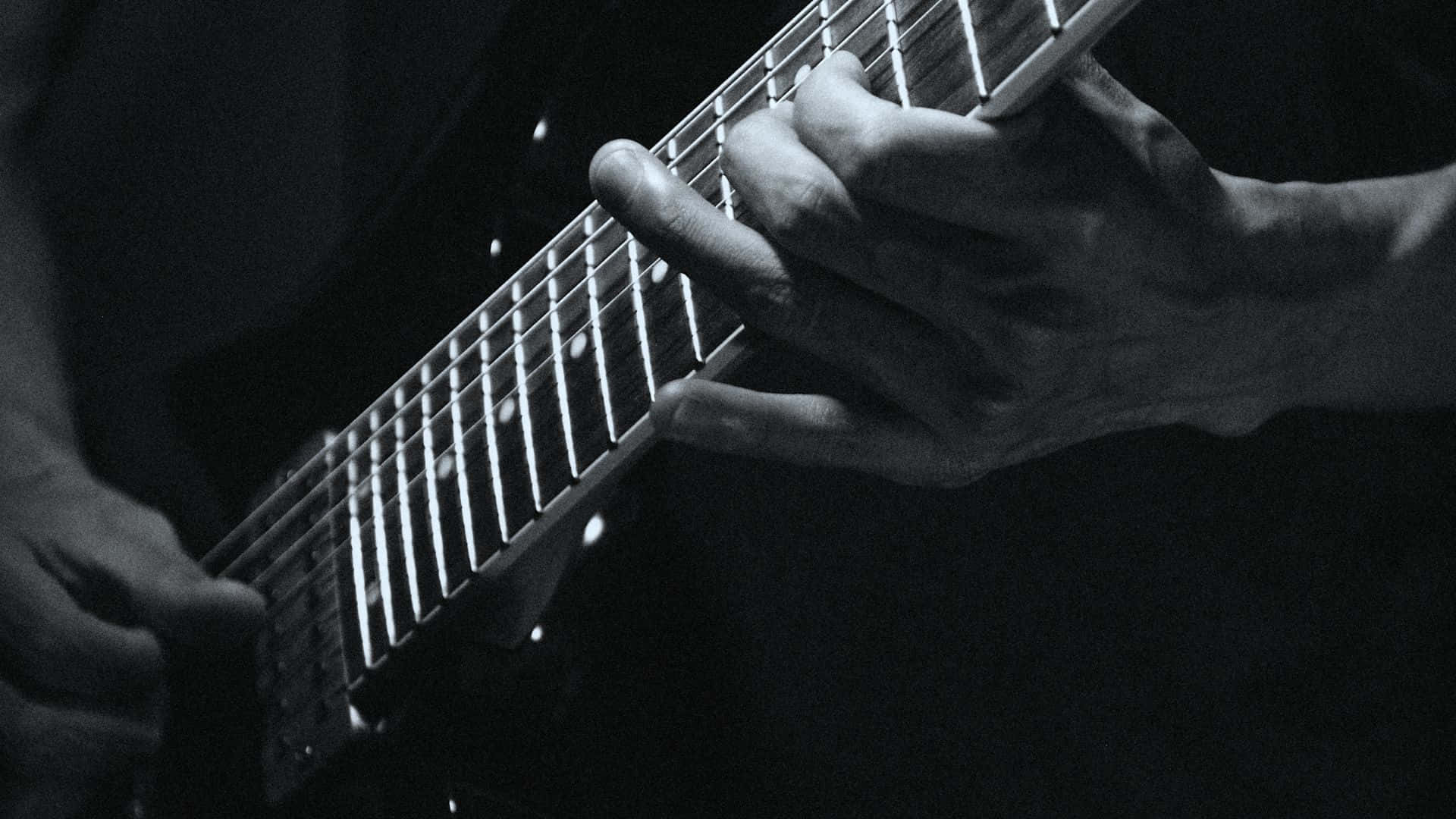 Black And White Guitar 桌布 壁紙 — 在戲劇性的舞台燈光下，雙手熟練地彈奏電結他的黑白特寫。