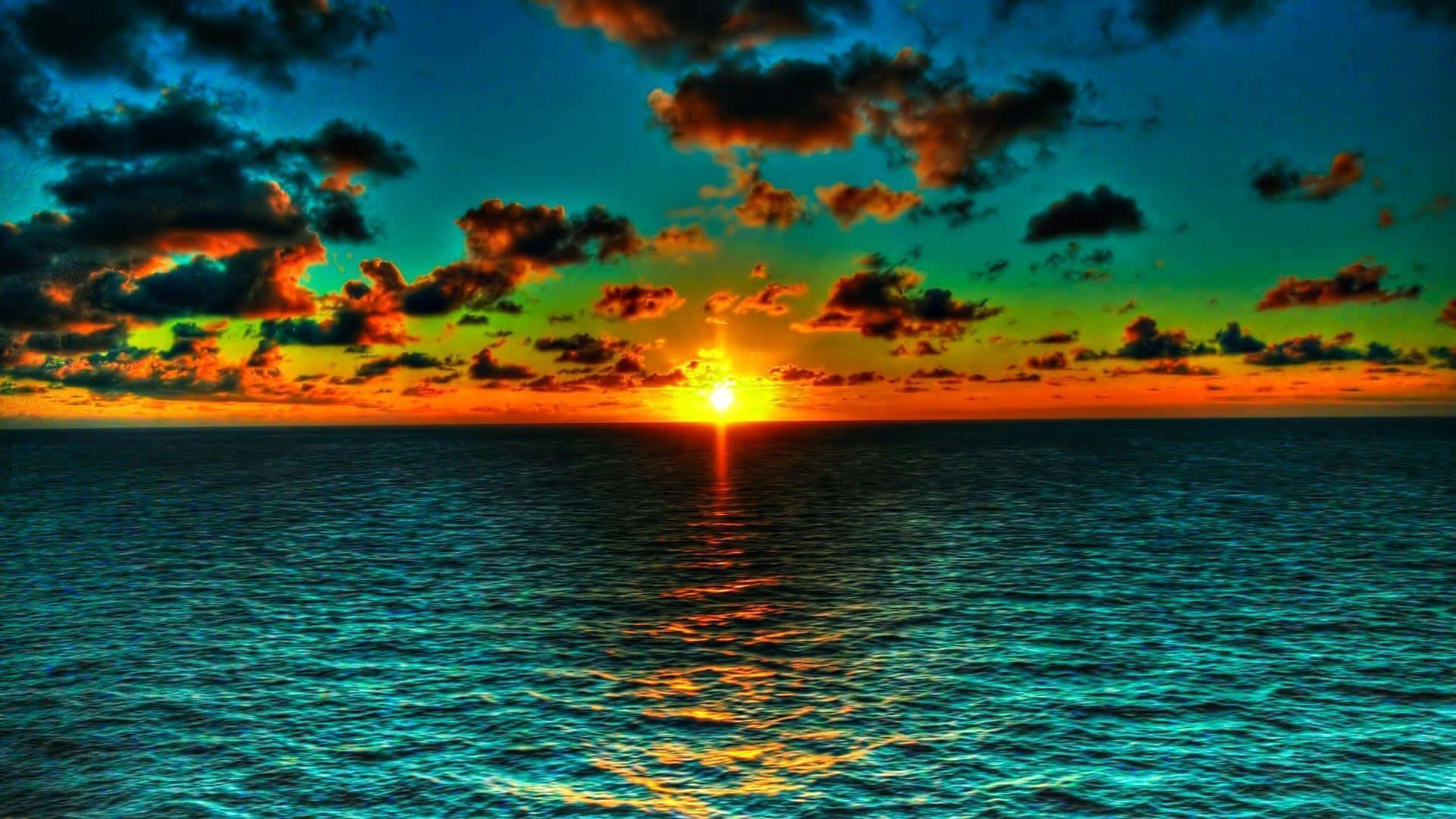 Beautiful Ocean 桌布 壁紙 — 在戲劇性的雲層下，一輪火紅的橙色太陽在碧綠的海浪上投下金色倒影，呈現出充滿活力的海上日落。