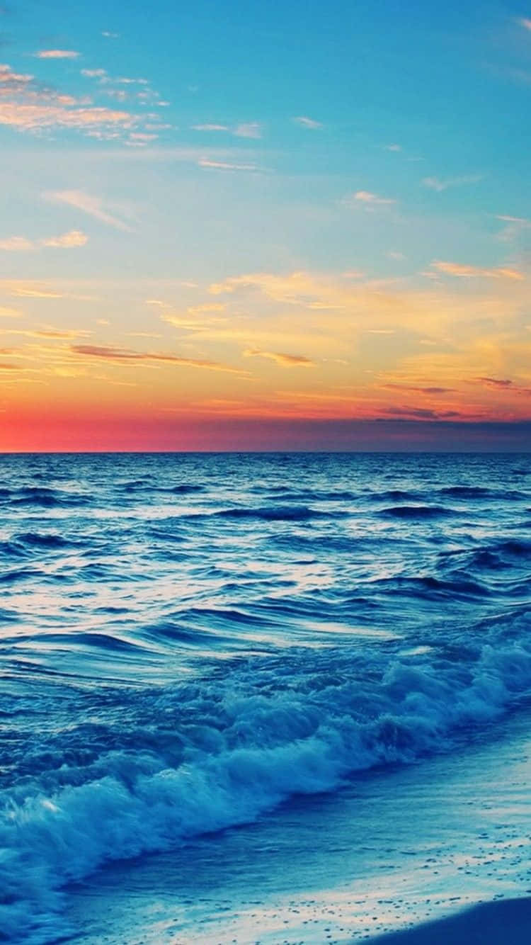在日落海灘捕捉夕陽最後的餘暉 壁紙 — 夕陽將天空染成火熱的橙色和粉紅色，映照在平靜的海洋上，溫柔的海浪拍打著沙灘。