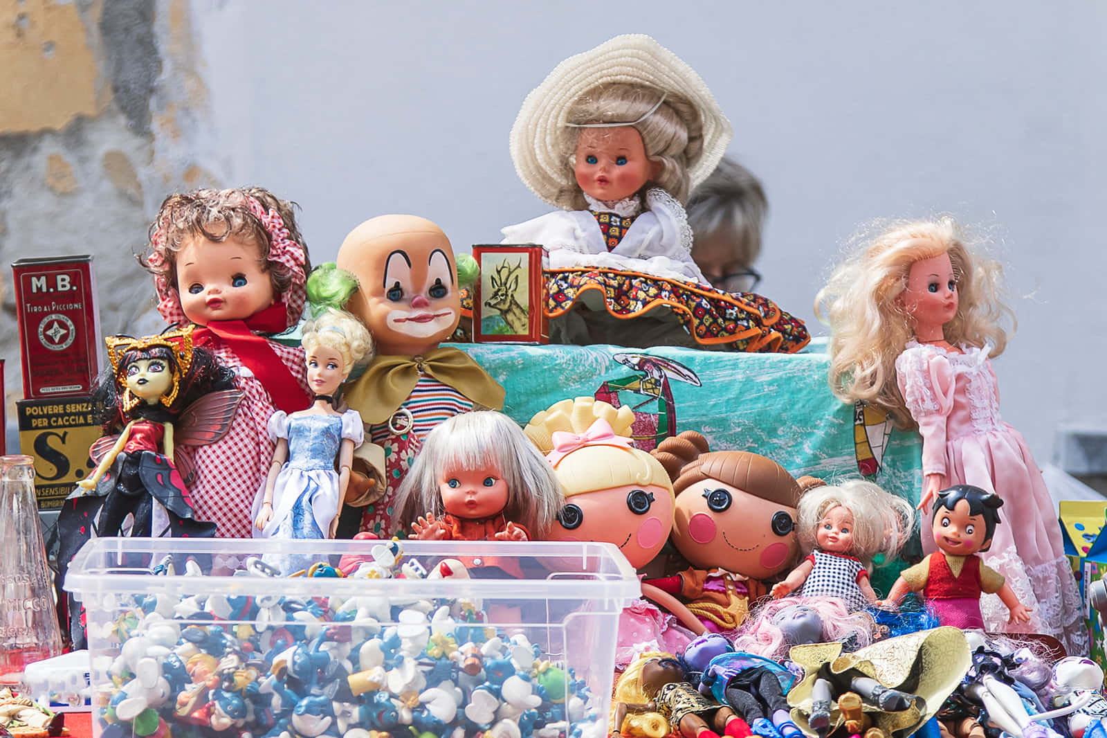 Dolls 桌布 壁紙 — 在明亮的日光下，市場攤位上堆滿了色彩繽紛的復古娃娃和玩具。