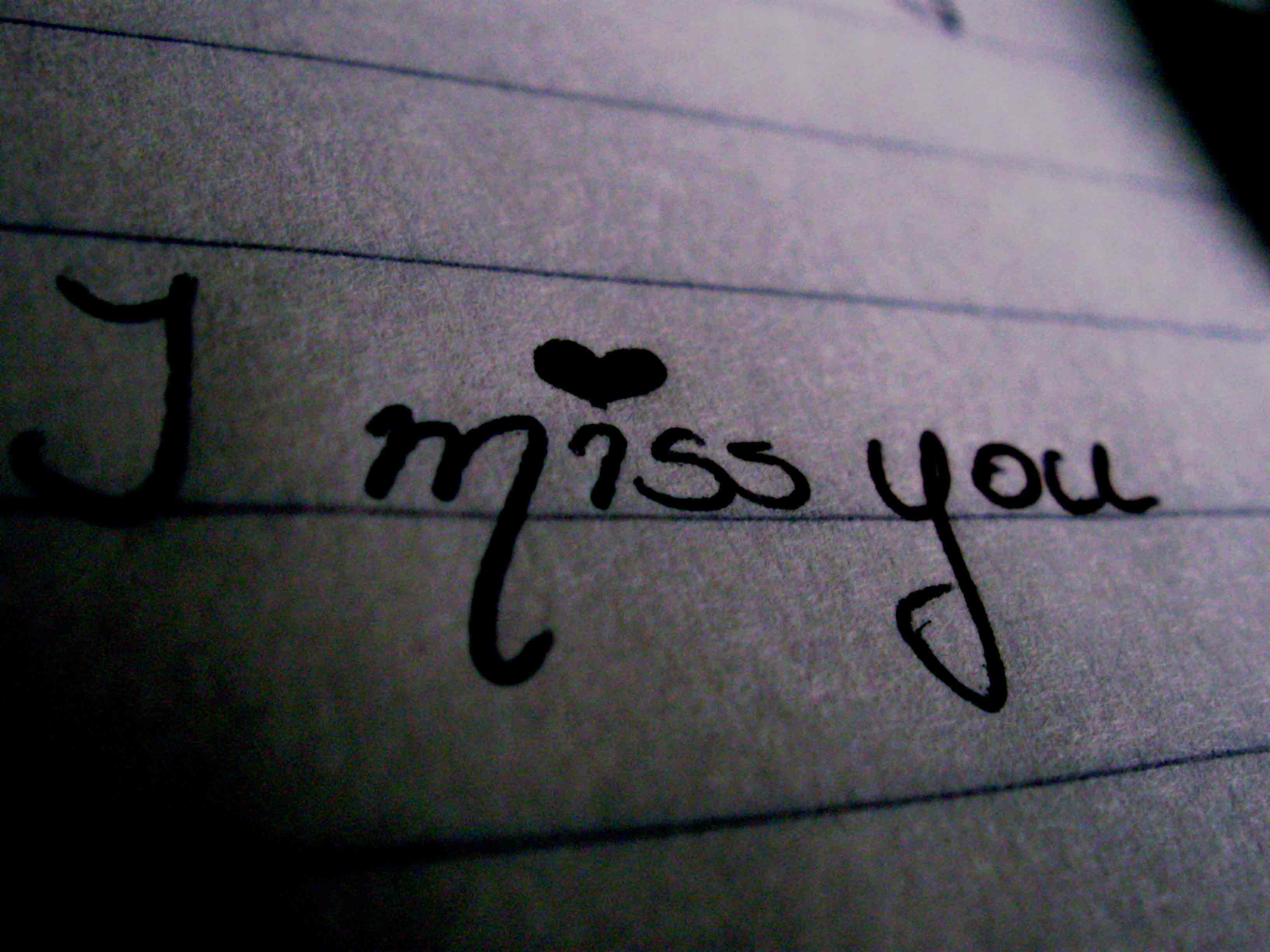 I Miss You 桌布 壁紙 — 在昏暗燈光下，橫線紙上手寫的「我想你」字條，i 上方有一顆心。