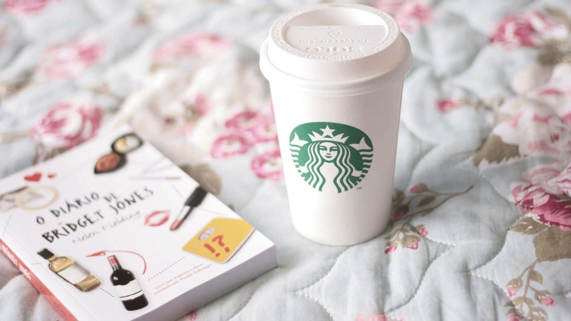 Starbucks咖啡杯同《BJ單身日記》書本喺花紋絎縫床罩上面。
