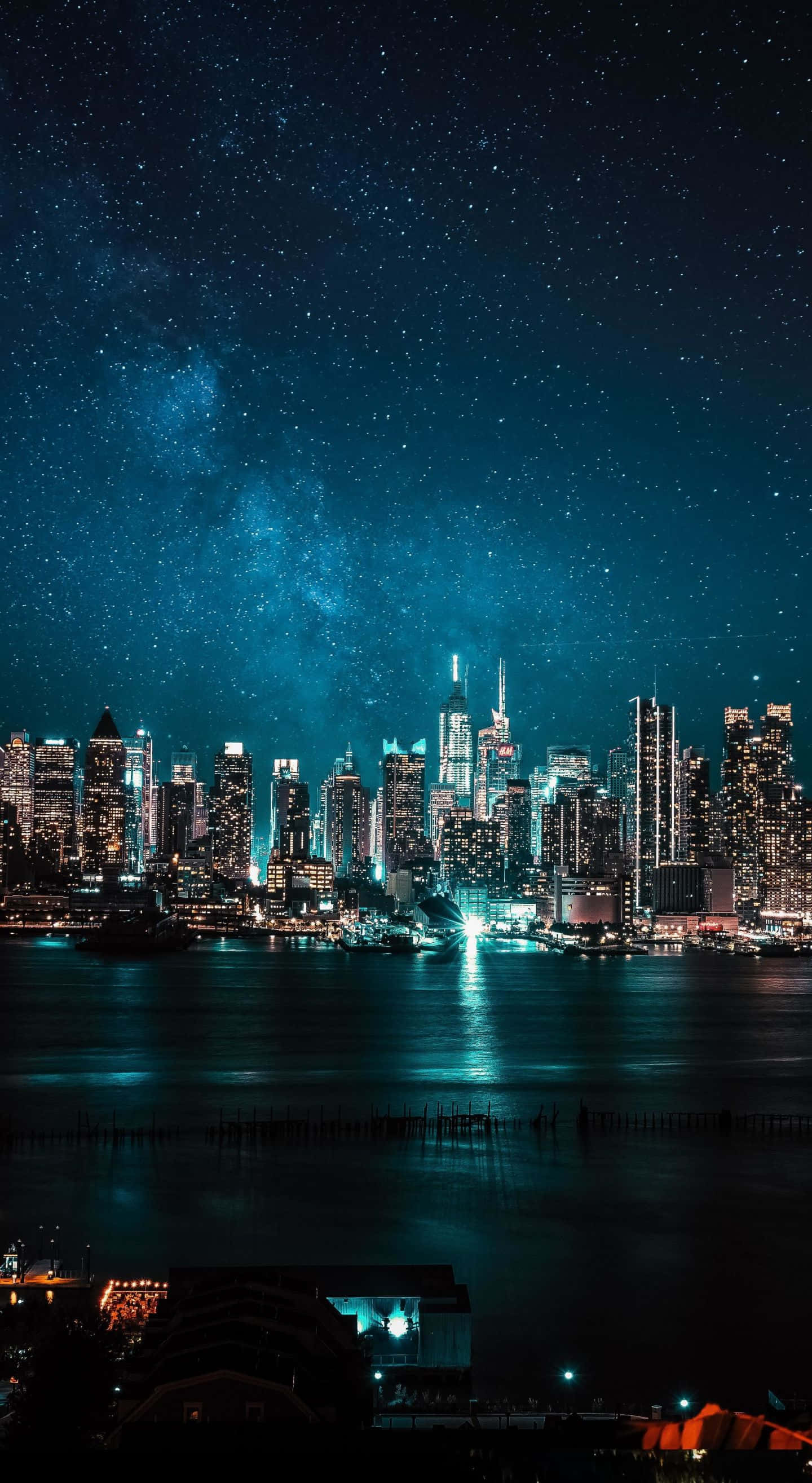 Cityscape 桌布 壁紙 — 在星空下，銀河在水面上閃耀，令人目眩神迷的城市天際線夜景。