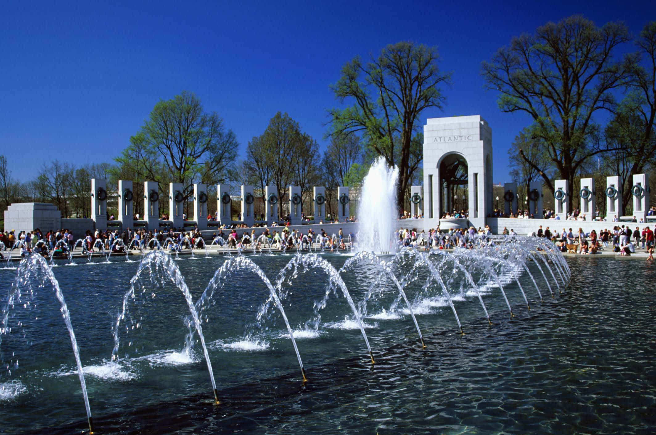 Memorial 桌布 壁紙 — 在晴朗的藍天下，一座宏偉的噴泉在大西洋牆紀念碑前優雅地拱起。