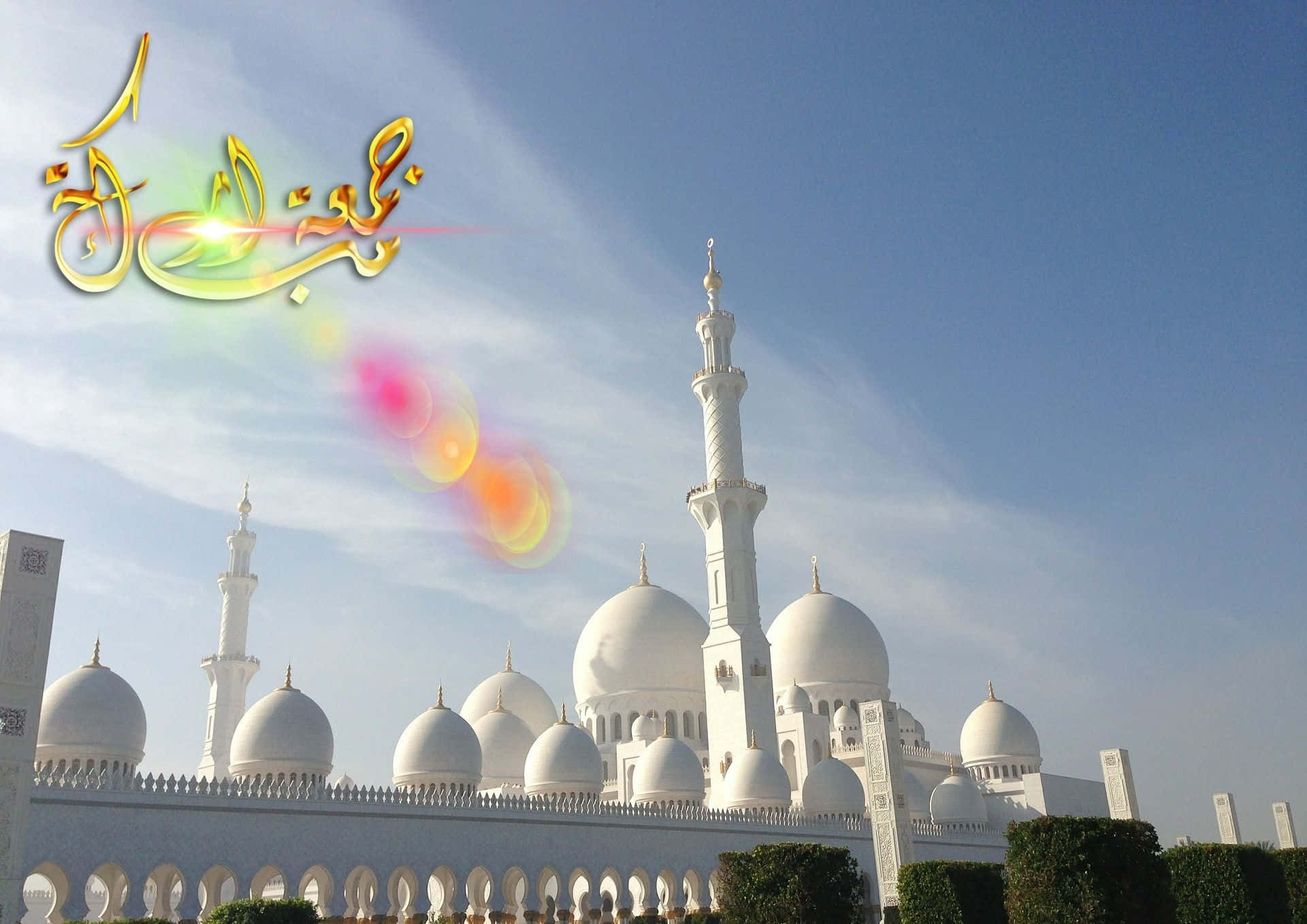 Jumma Mubarak 桌布 壁紙 — 在晴朗藍天下，帶有圓頂和宣禮塔的白色大清真寺，飾有金色阿拉伯書法和鏡頭光暈。