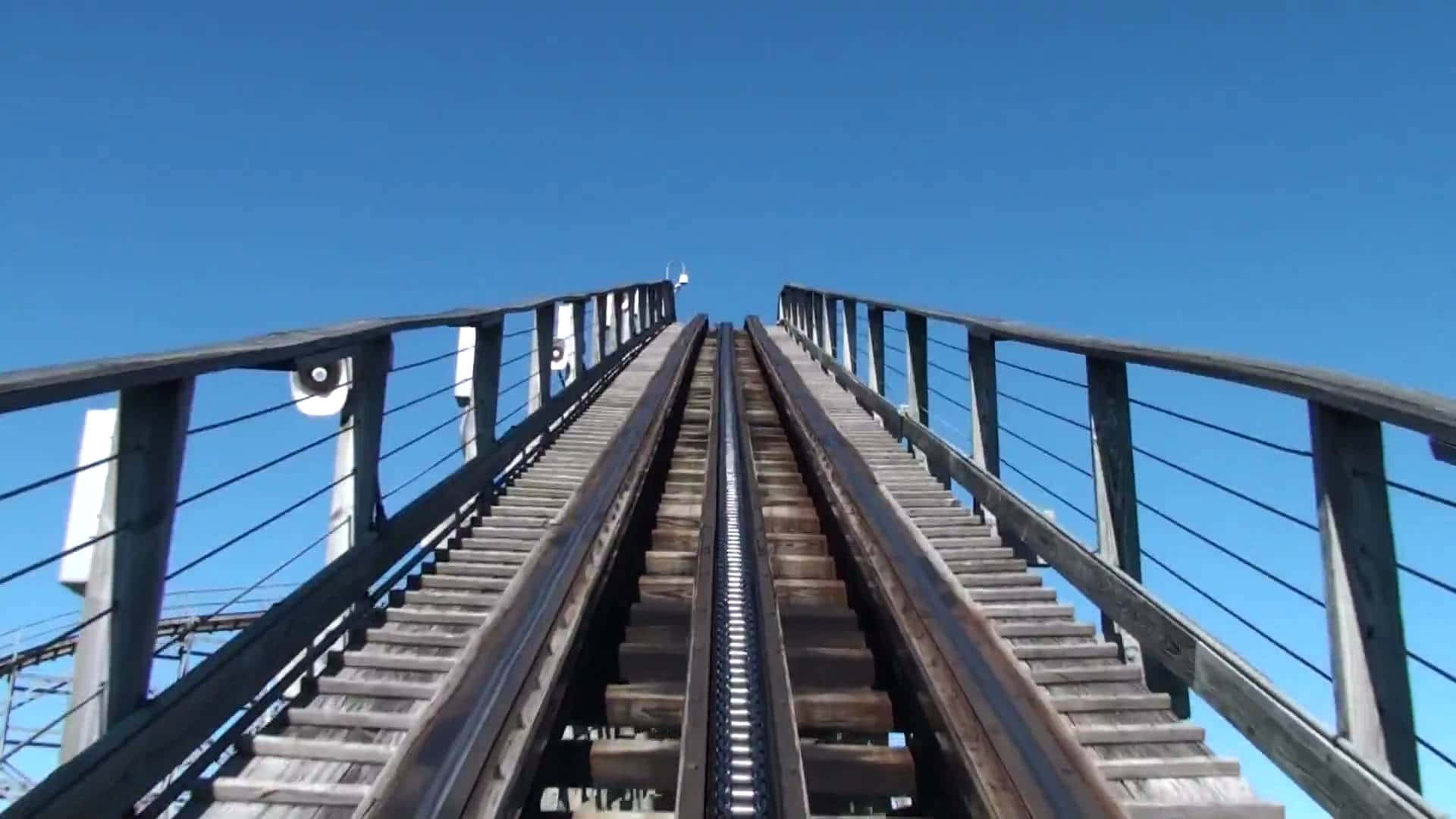 過山車 桌布 壁紙 — 在晴朗藍天下以第一人稱視角攀爬木製雲霄飛車軌道的刺激體驗。