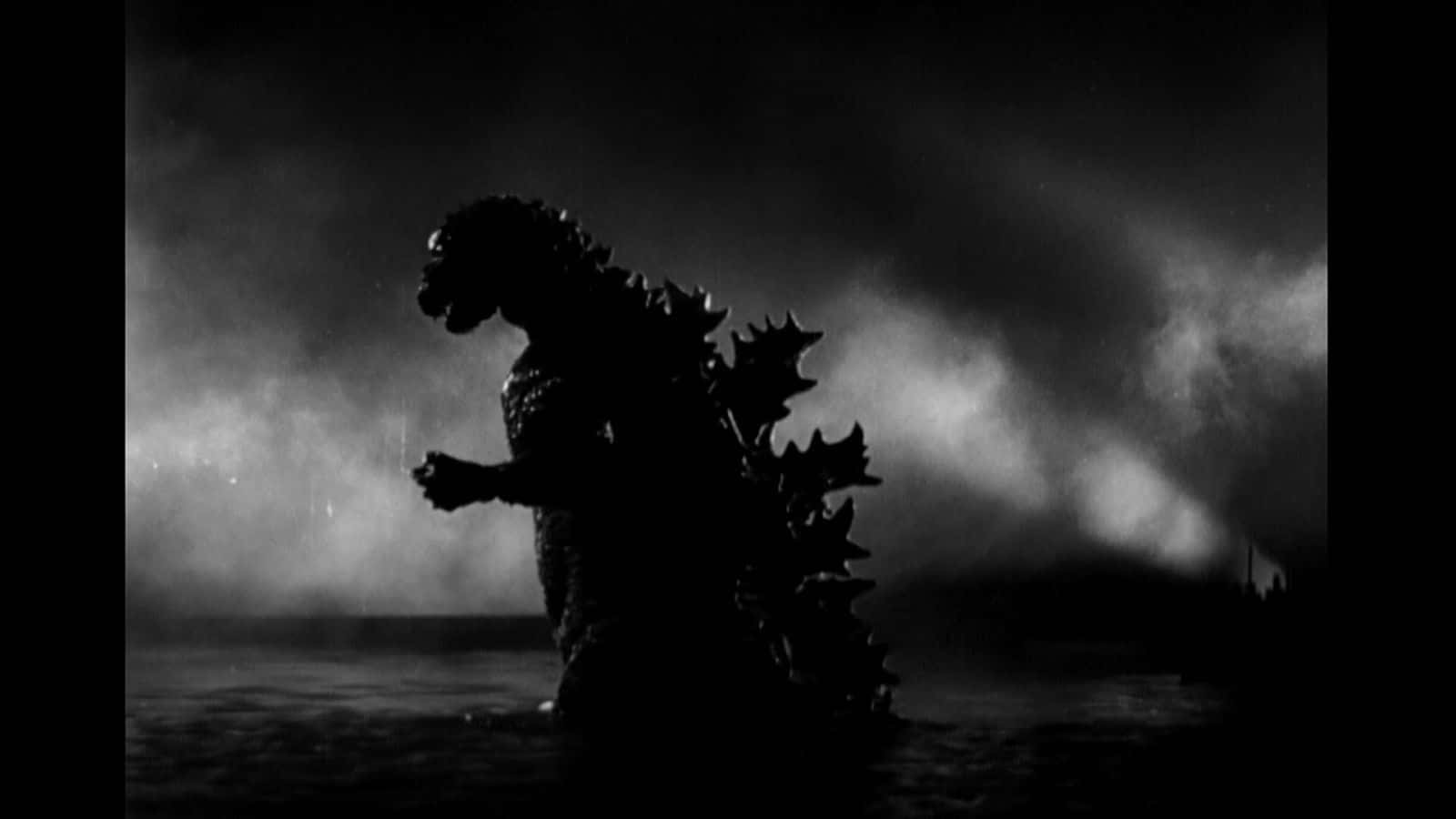 Godzilla 1954 桌布 壁紙 — 在暴風雨夜空的戲劇性背光下，高聳的哥斯拉剪影從水中浮現。