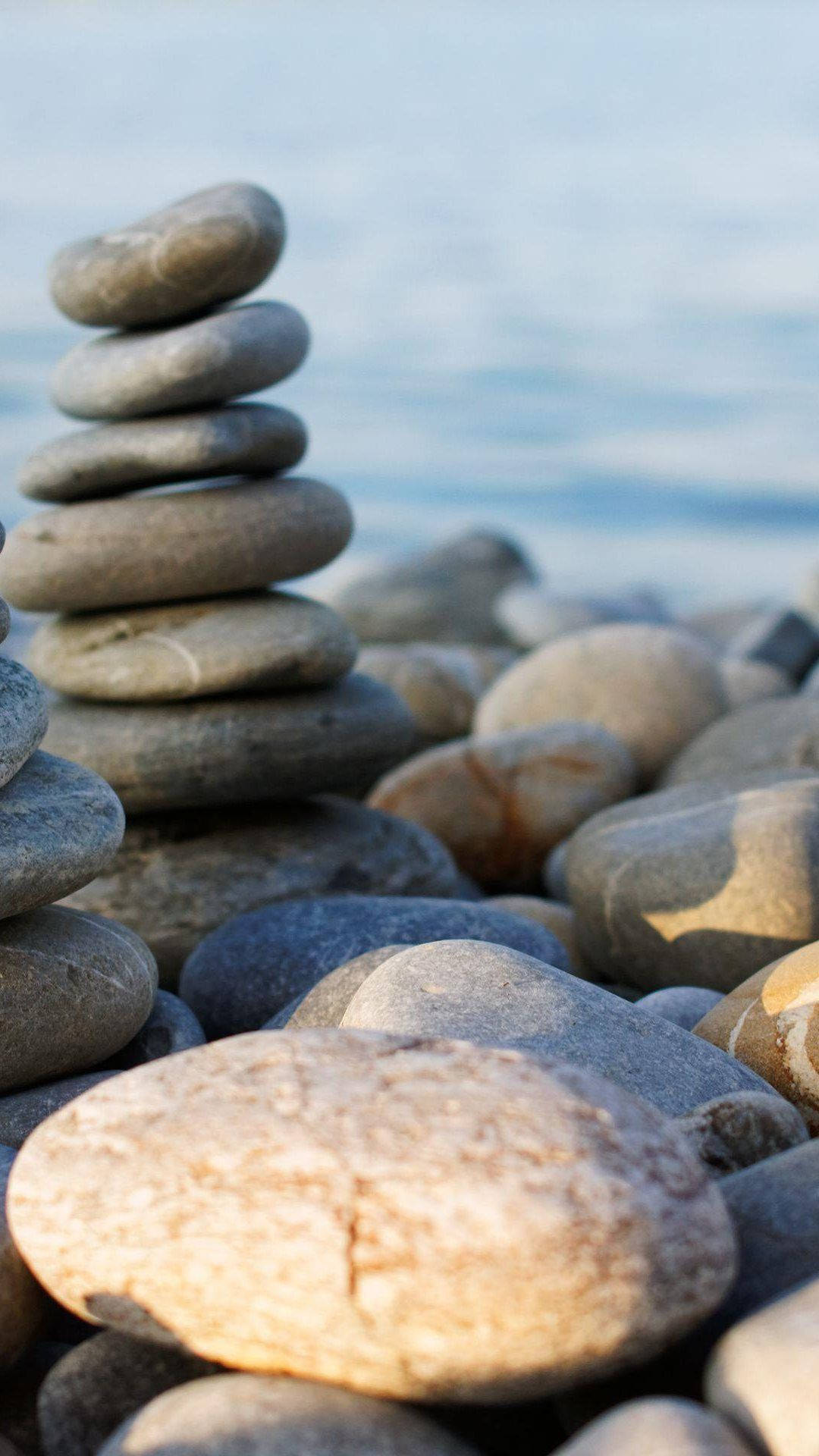Meditation 桌布 壁紙 — 在柔和日光下，平靜水邊平衡堆疊的平滑河石。