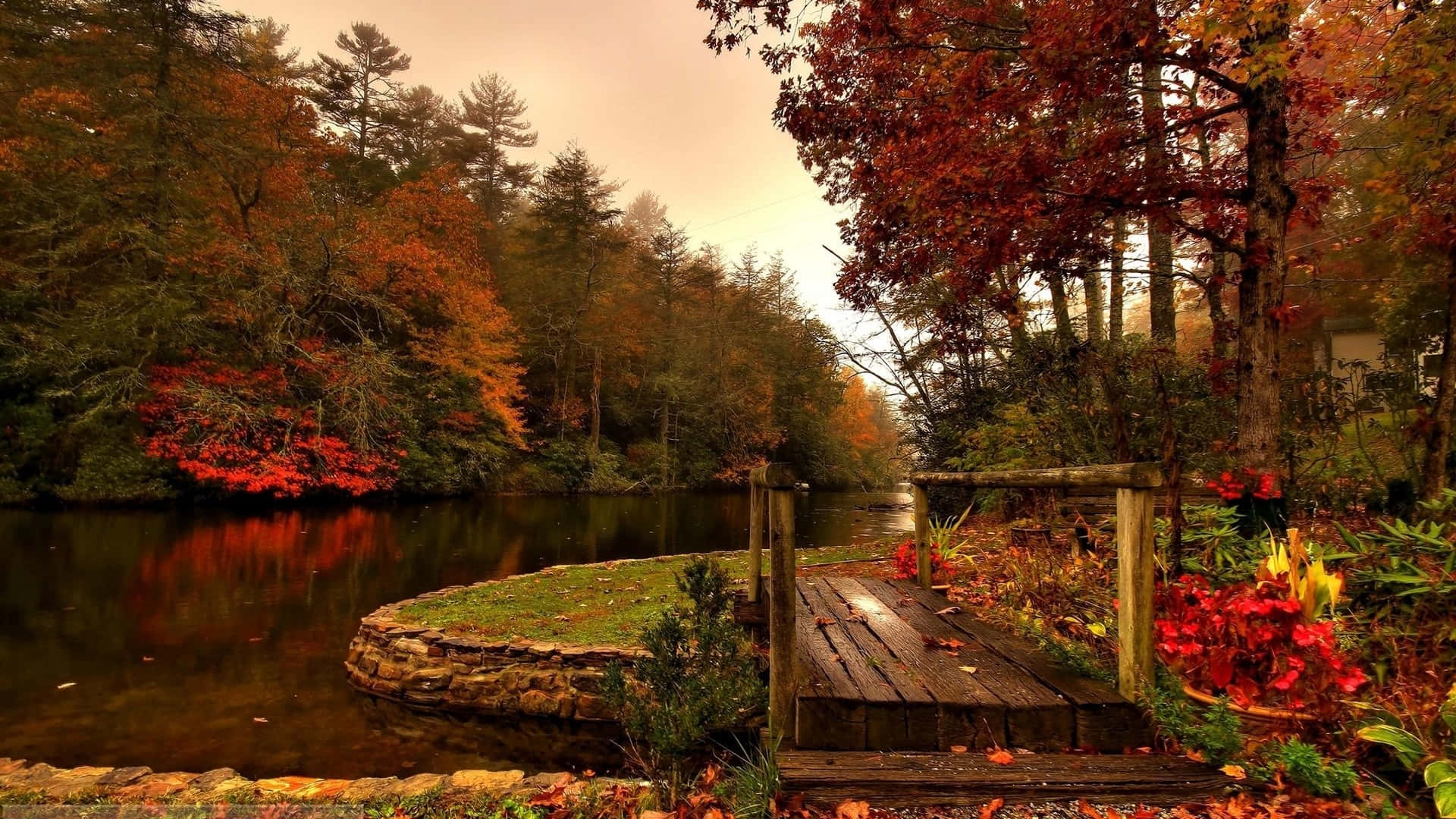 Fall Lake 桌布 壁紙 — 在柔和的多雲天空下，一個木製碼頭延伸到平靜的河流中，周圍環繞著充滿活力的秋葉。