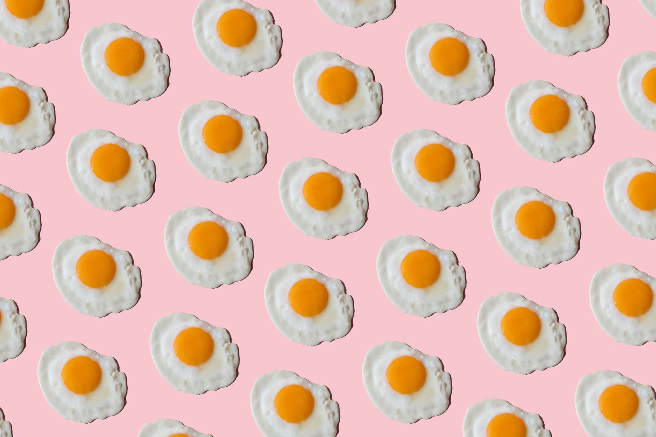 Egg 桌布 壁紙 — 在柔軟的粉紅色背景上重複的太陽蛋圖案。