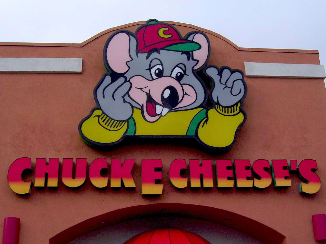 Chuck E Cheese's的吉祥物老鼠從建築物上色彩繽紛的招牌揮手。