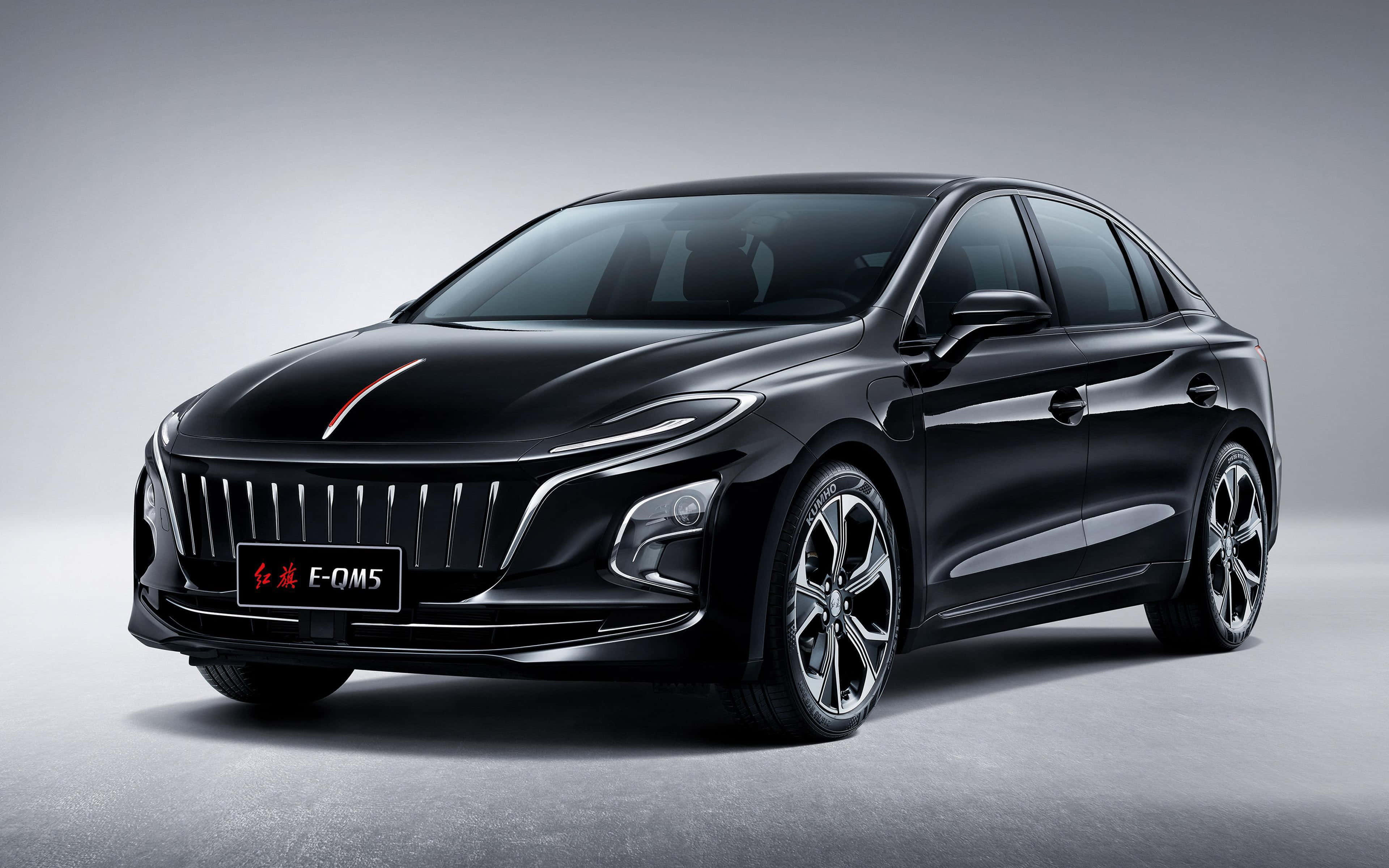 Hongqi 桌布 壁紙 — 在極簡工作室環境中展示的時尚黑色Hongqi E-QM5電動轎車，帶有鍍鉻飾條和紅色條紋。