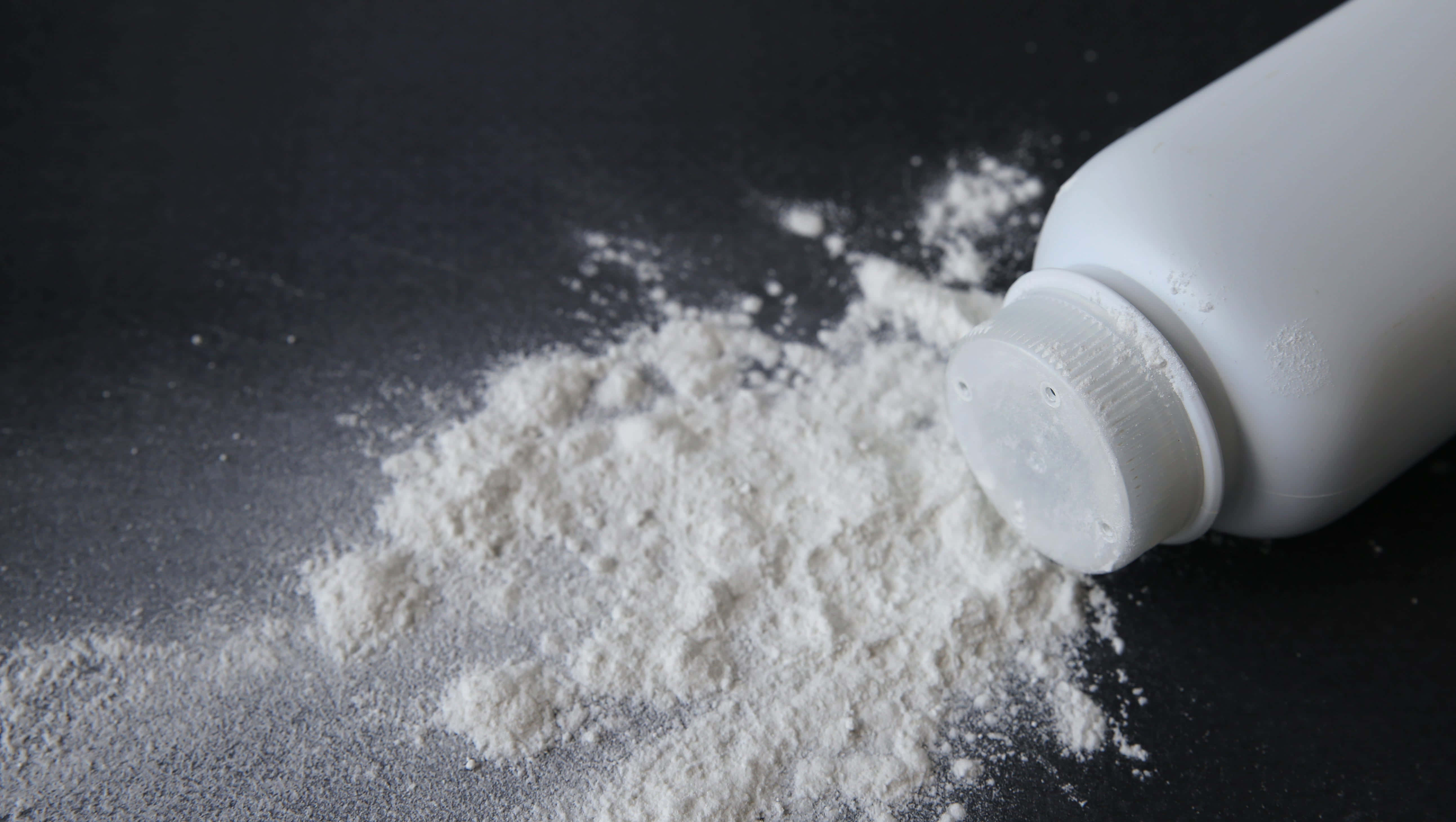 Baby Powder 桌布 壁紙 — 在極簡風格的近距離拍攝中，白色粉末從傾斜的瓶子灑落到深色紋理表面上。