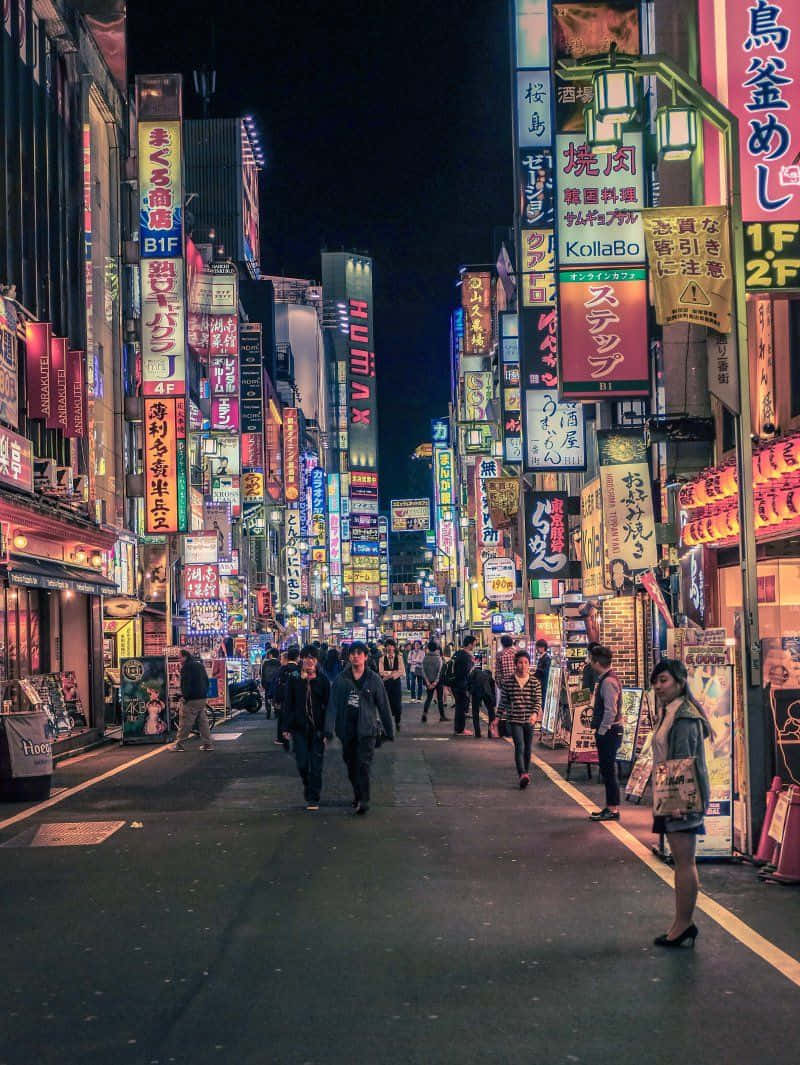 在歐洲探索中創造難忘回憶 壁紙 — 夜晚東京繁華的霓虹燈街道，行人走在發光的招牌和高樓大廈下。