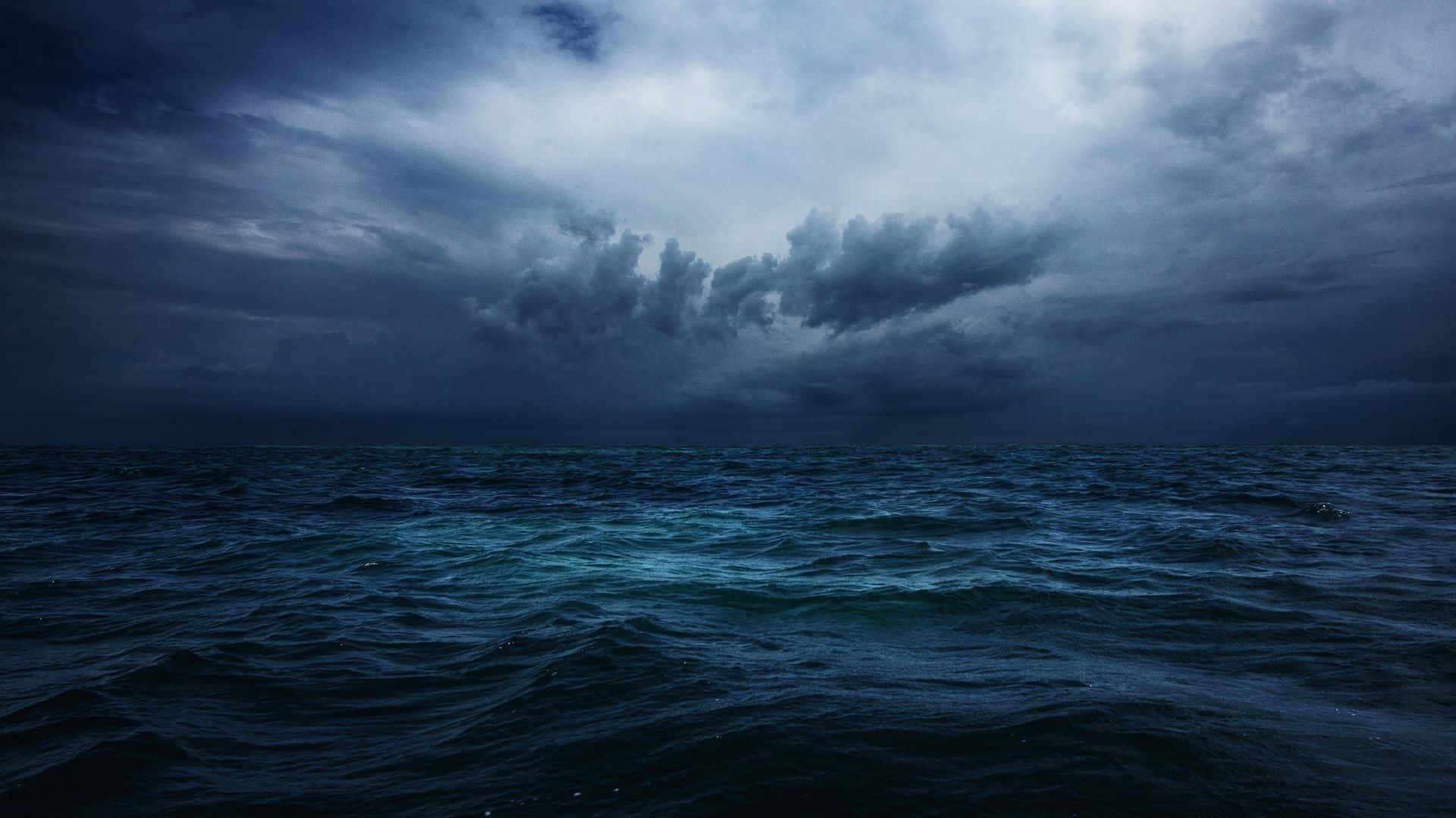 Dark Ocean 桌布 壁紙 — 在沉重陰暗的天空下，波濤洶湧的海洋，伴隨著不祥的雲層和起伏的藍色波浪。