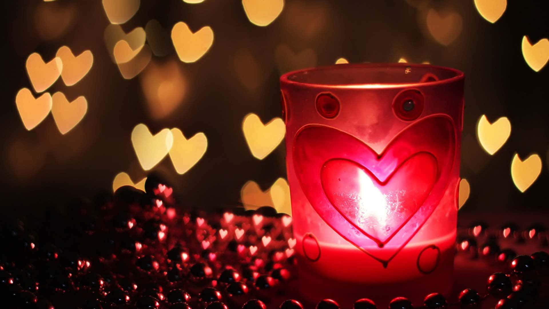可愛情人節gif 桌布 壁紙 — 在浪漫的環境中，一個發光的紅色心形蠟燭，周圍散落著紅色珠子和金色心形散景燈光。