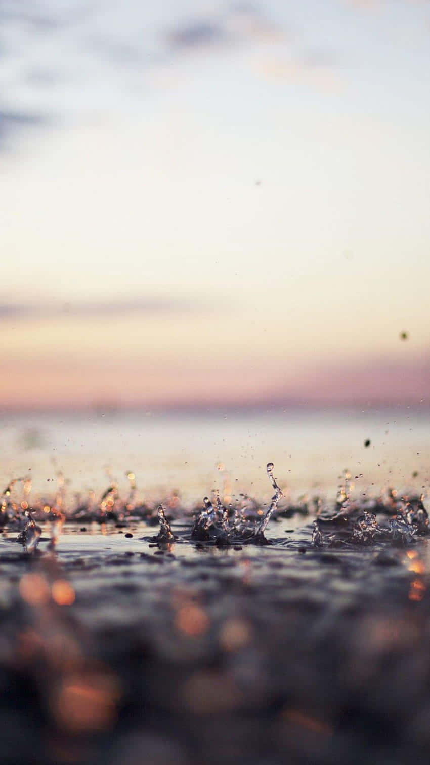 雨滴在潮濕的地面上飛濺，日落時分柔和粉彩的天空。