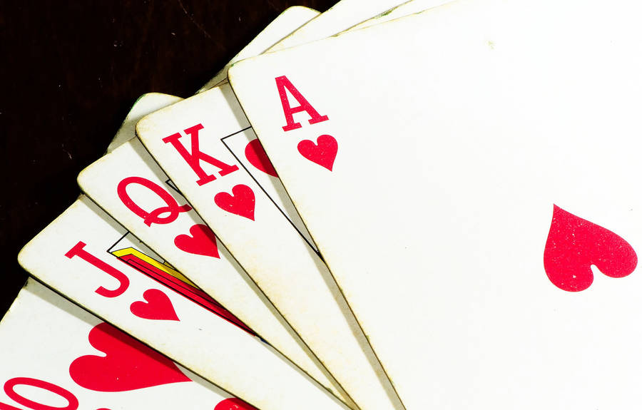 Poker 桌布 壁紙 — 在深色木質表面上，紅心啤牌以扇形展開，顯示A、K、Q、J及10。