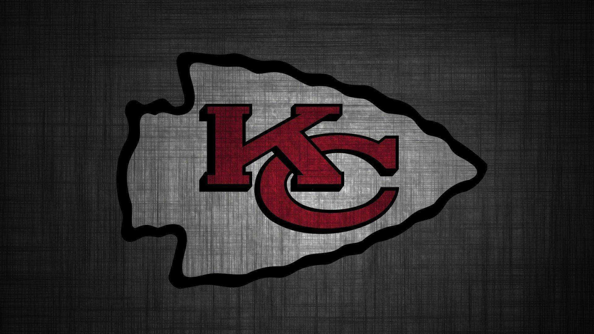 Kansas City Chiefs 桌布 壁紙 — 在深色紋理背景上，一個大膽的紅色和銀色堪薩斯城酋長隊標誌。