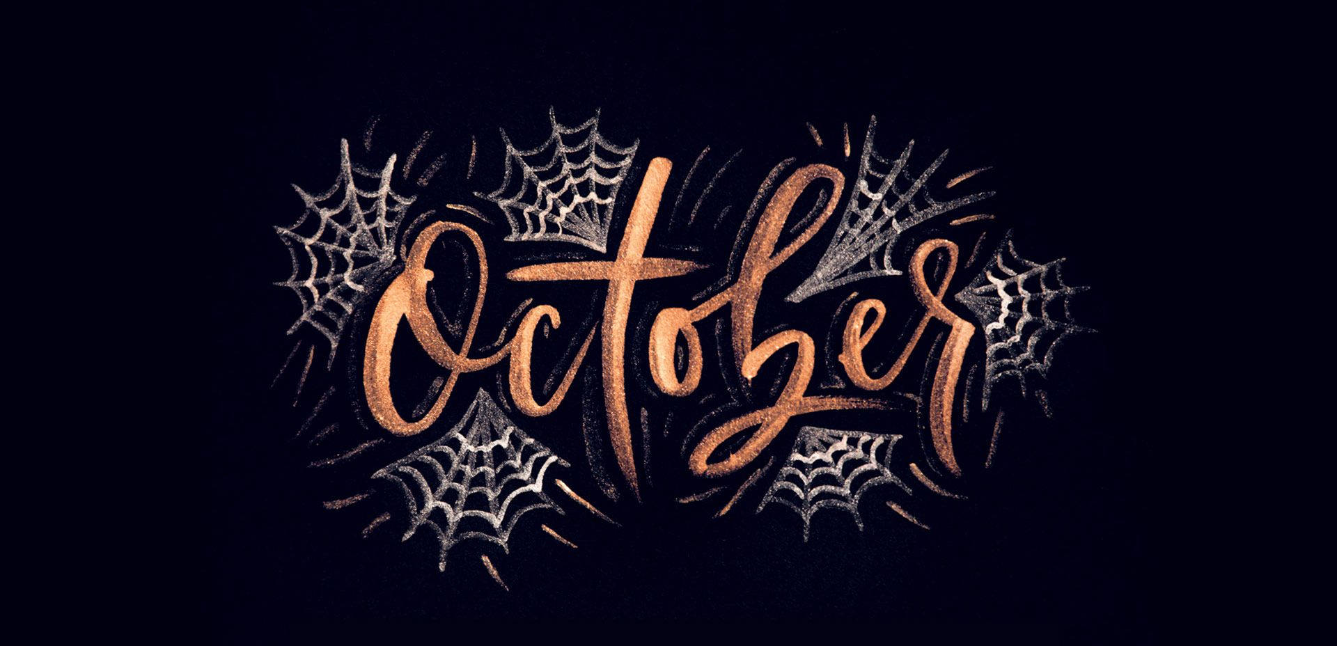 萬聖節 桌布 壁紙 — 在深色背景上，優雅的銅色字體寫著「October」，周圍環繞著複雜的銀色蜘蛛網。