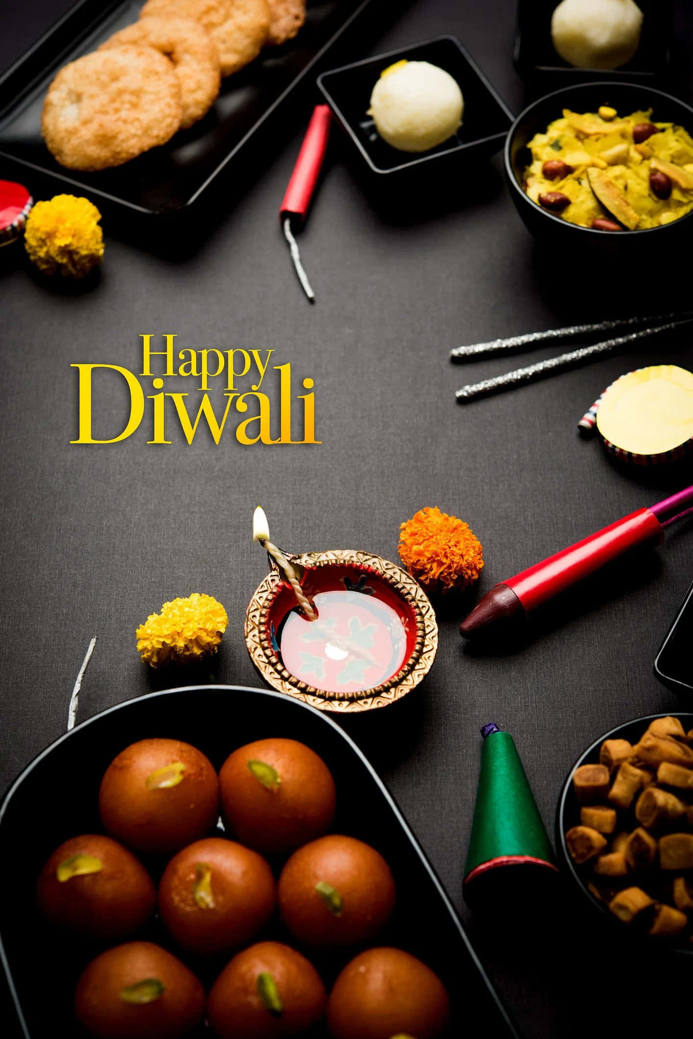 Happy Diwali 桌布 壁紙 — 在深色表面上擺放著發光的迪亞、糖果、餅乾和金盞花的節日排燈節桌面展示。