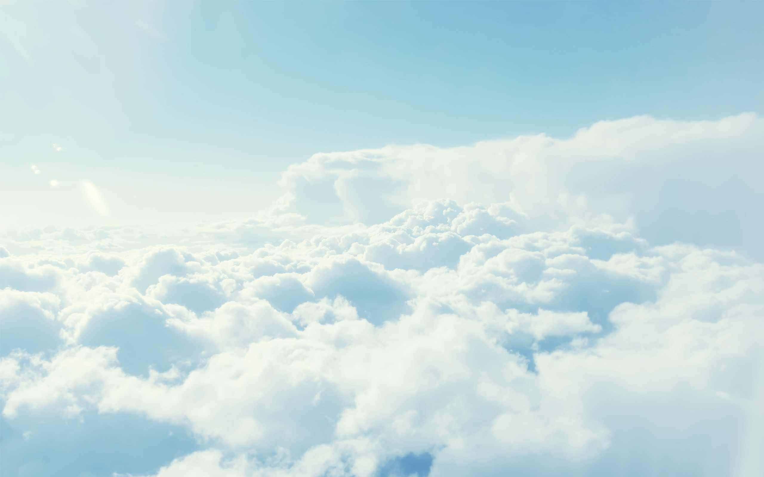 Cloud Aesthetic 桌布 壁紙 — 在清澈的藍天下，柔和的陽光穿透蓬鬆的白雲，呈現一片寧靜的景色。
