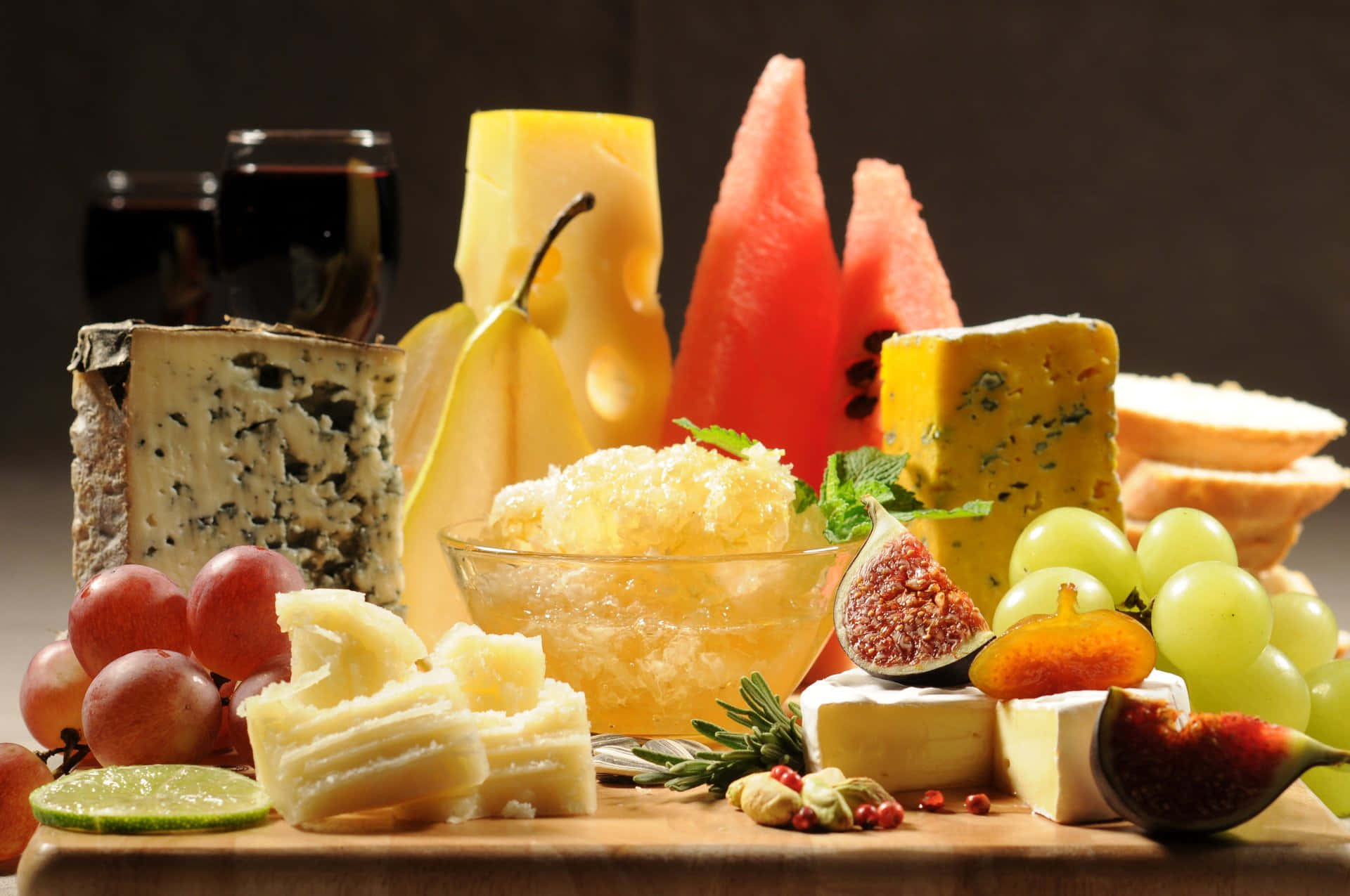 Food And Beverage 桌布 壁紙 — 在溫暖燈光下，一個豪華的熟食拼盤展示了各式芝士、水果、麵包和葡萄酒。