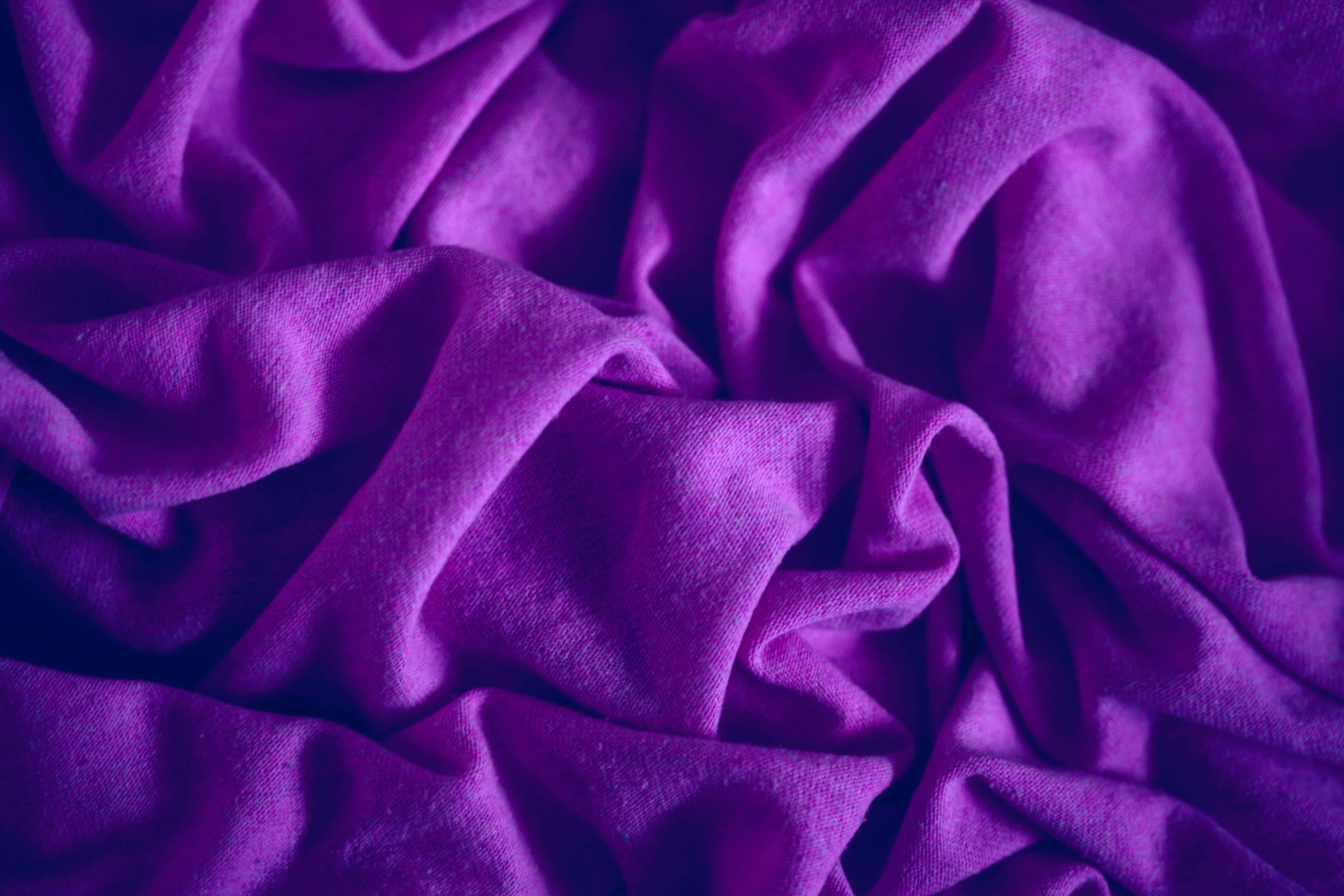 Purple Fabrics 桌布 壁紙 — 在溫暖燈光下，帶有深邃皺褶和柔軟質感的豐富紫色布料。