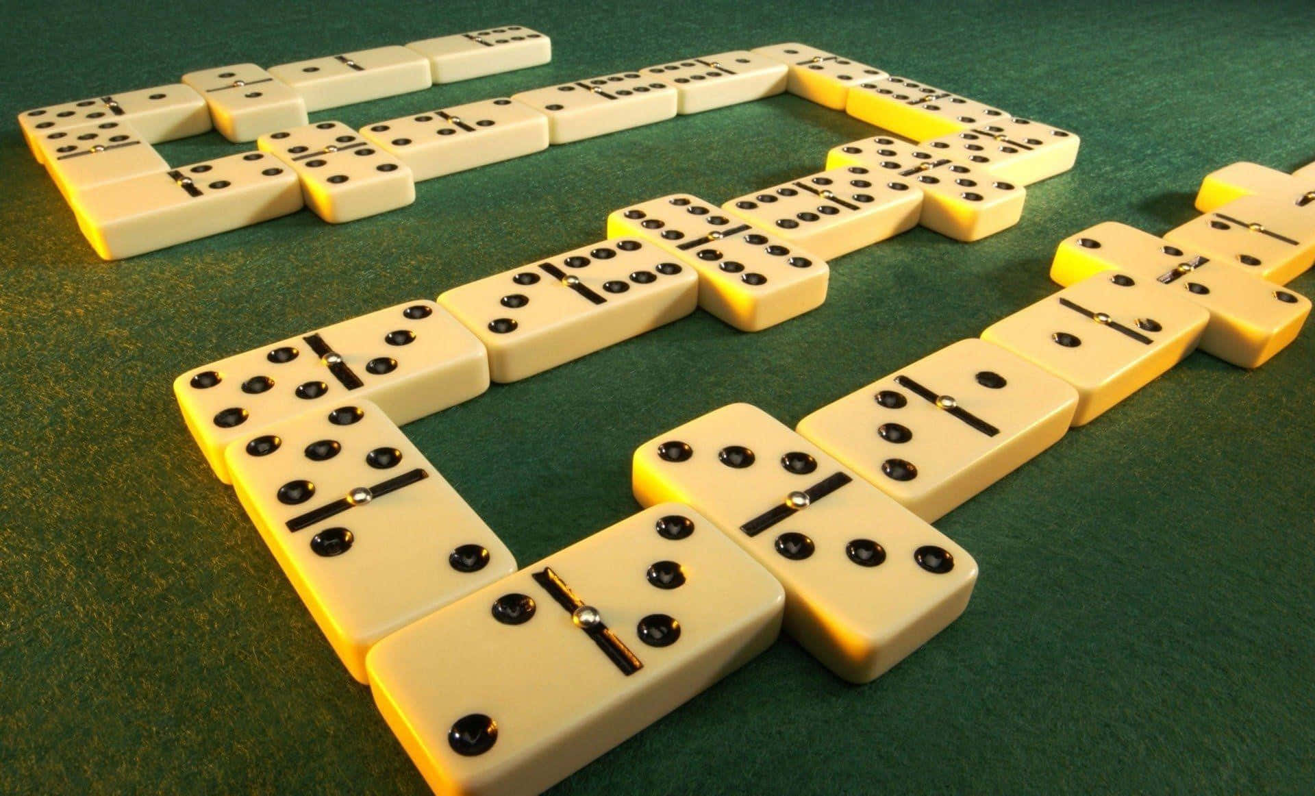 Domino 桌布 壁紙 — 在溫暖燈光下，綠色氈面上排列著一條彎曲的奶油色多米諾骨牌鏈，帶有黑色圓點。