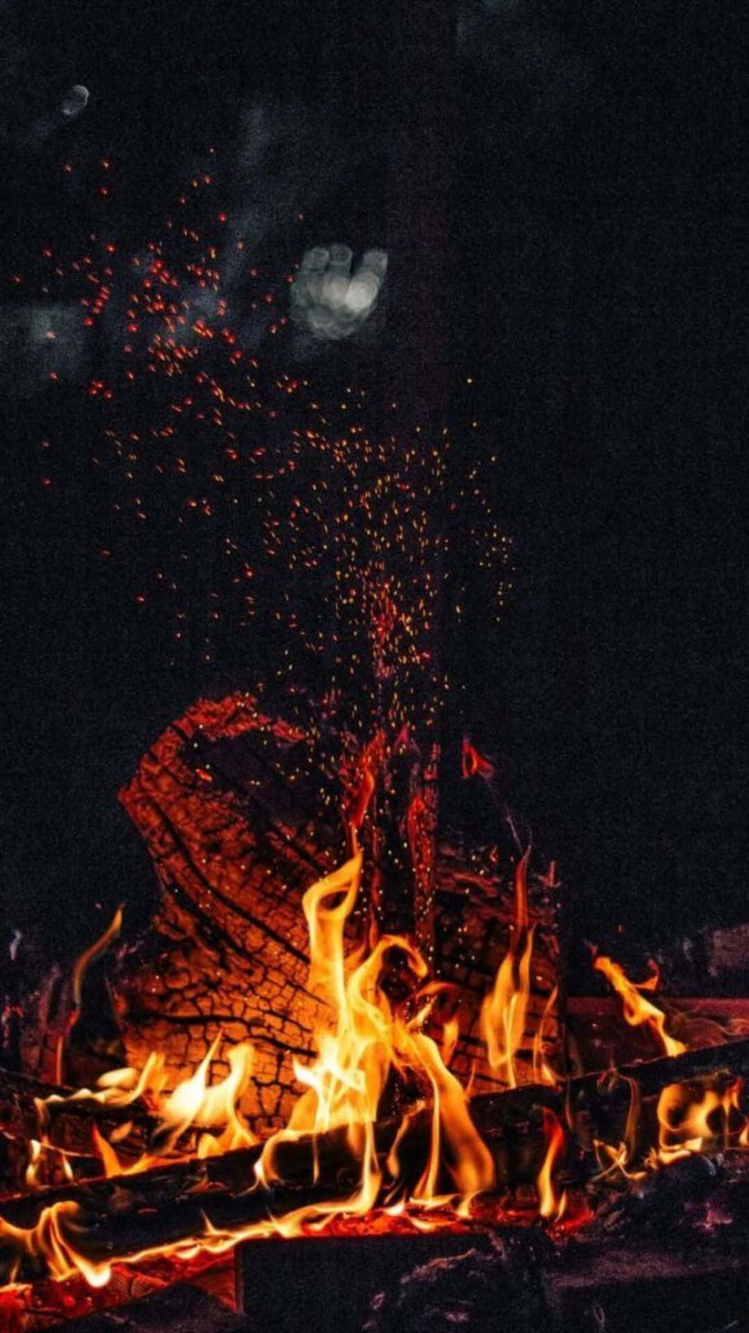 營火在夜間明亮燃燒，火花飛濺，上方可見月亮。