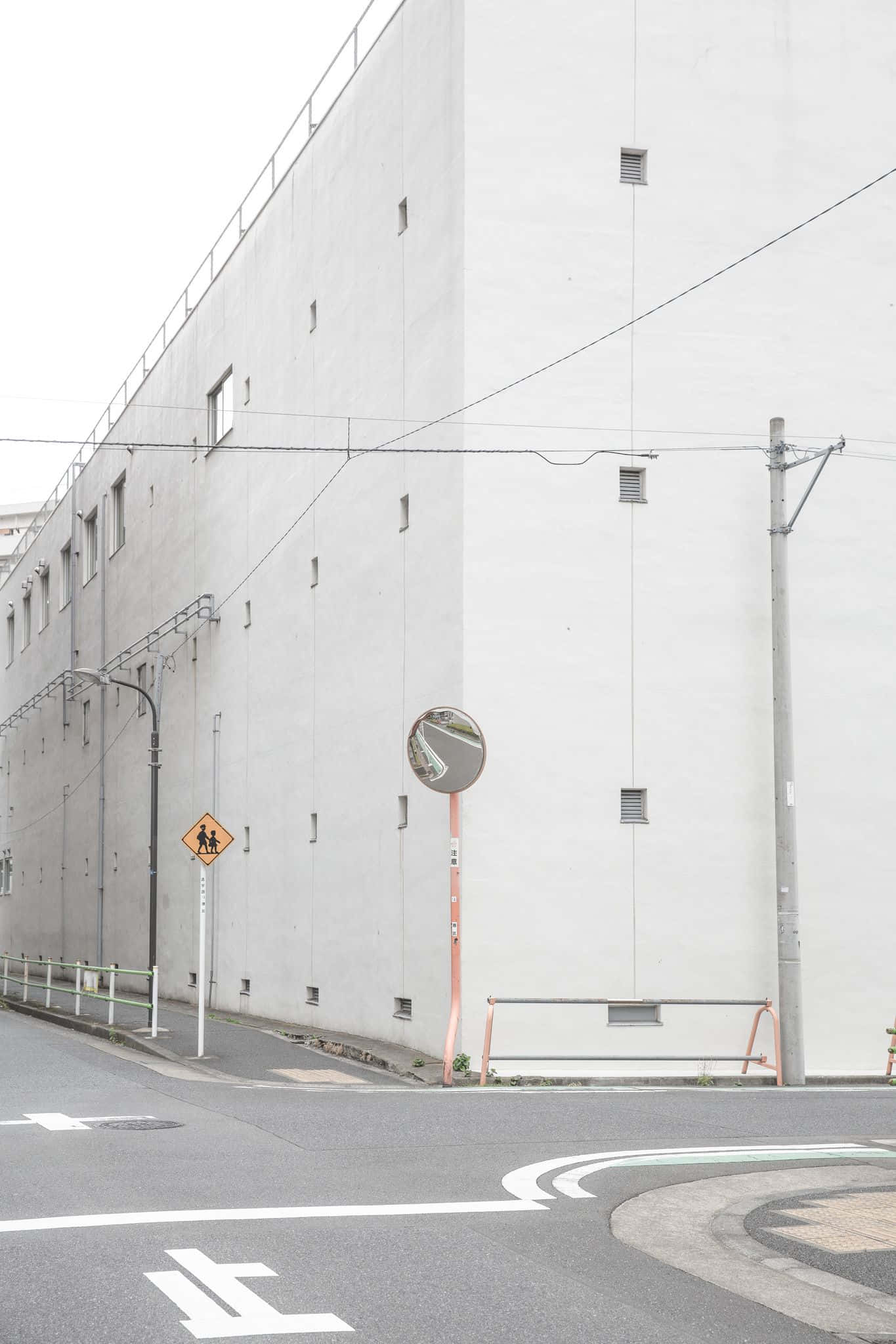 在灰色的簡約中發現美 壁紙 — 簡約城市街角，有一座大型白色建築、交通鏡和行人過路標誌，天空多雲。
