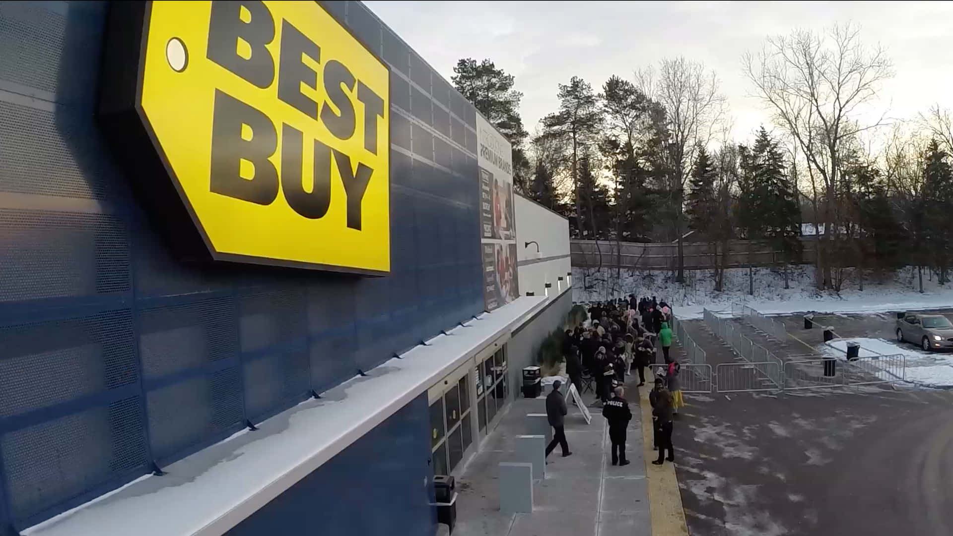 日落時分，在積雪的冬季停車場中，Best Buy商店外的人群。