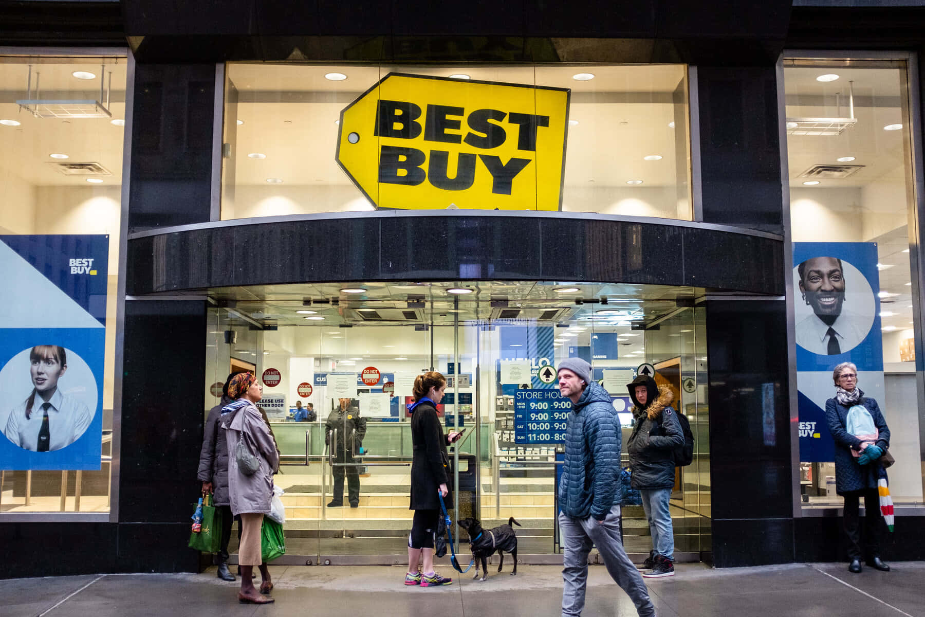 Best Buy商店外的人們，有玻璃門和黃色標誌