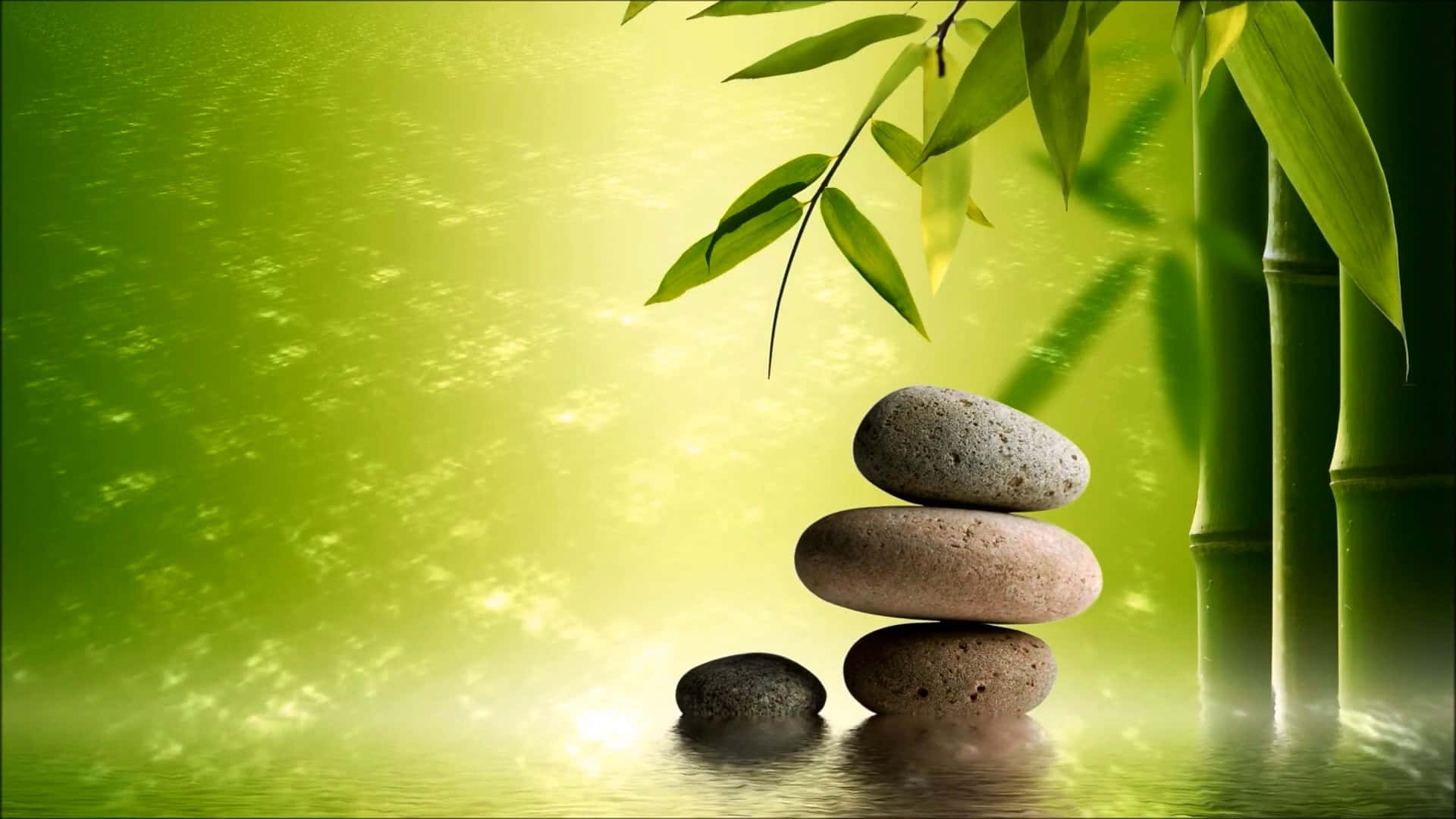 在禪的時刻尋得內在平靜與喜悅 壁紙 — 光滑的石頭堆疊在反射的水面上，旁邊是發光的竹莖，沐浴在柔和的金色光線下。