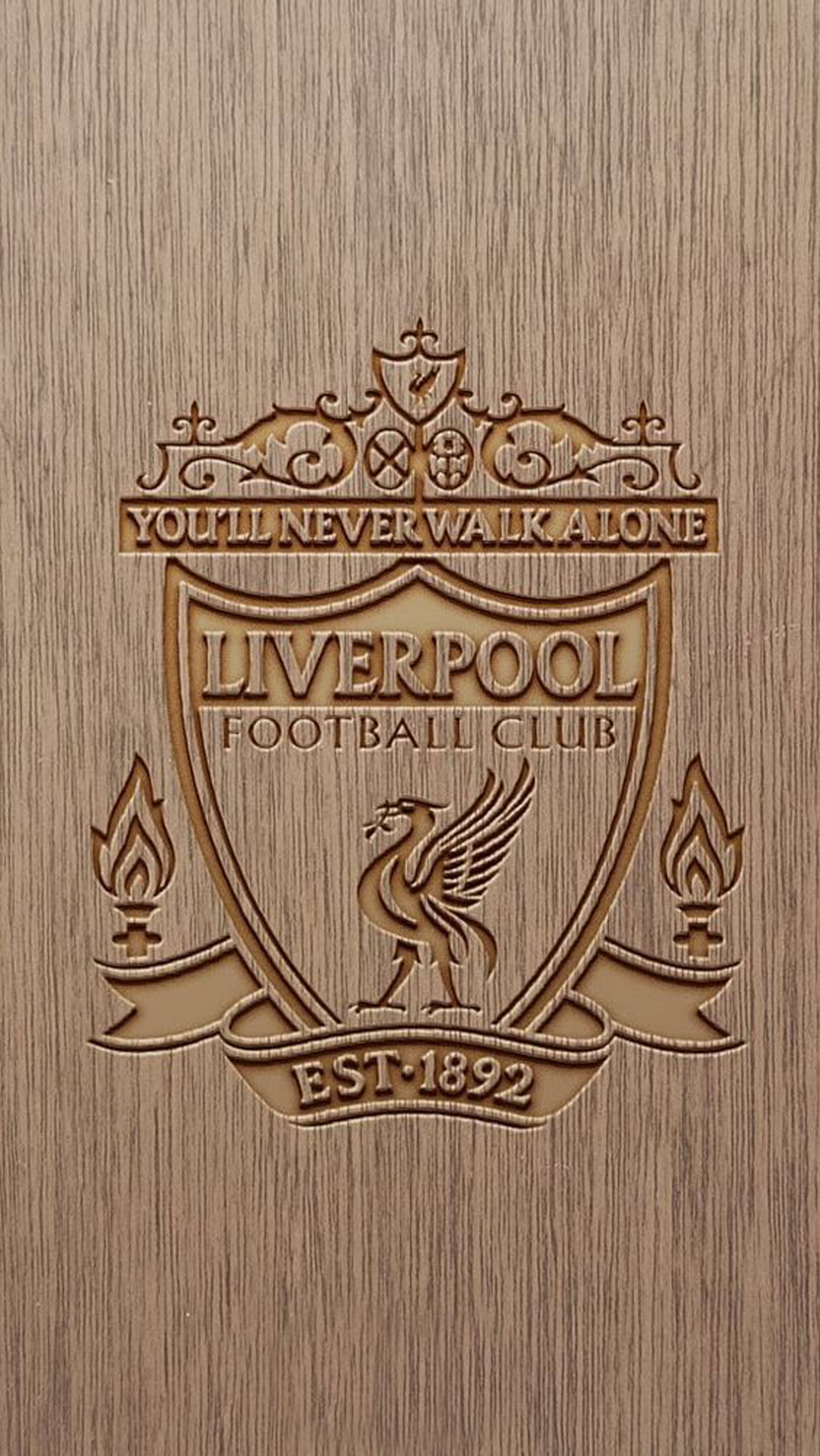 Liverpool Fc 桌布 壁紙 — 在紋理木背景上，利物浦足球會徽章的詳細木刻，附有「You'll Never Walk Alone」格言。