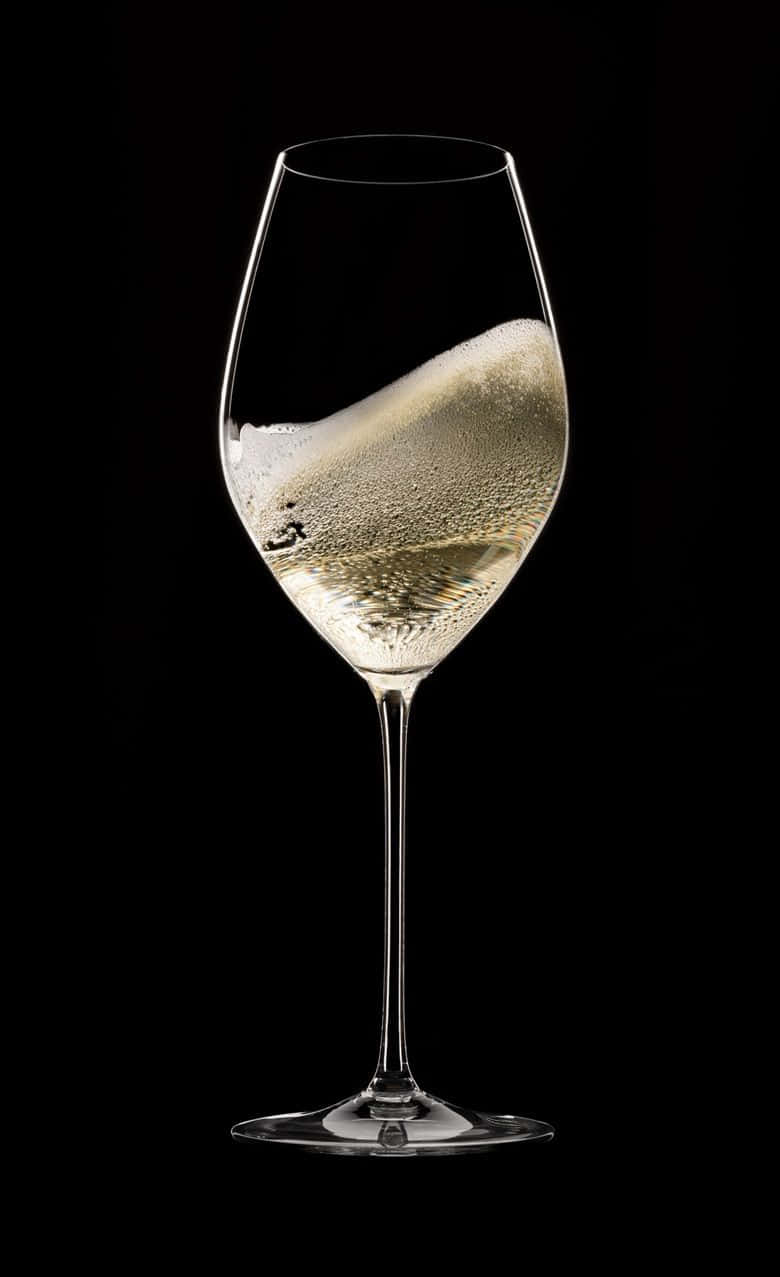 White Wine 桌布 壁紙 — 在純黑背景上，一隻盛滿閃爍金色液體和上升氣泡的香檳笛形杯。