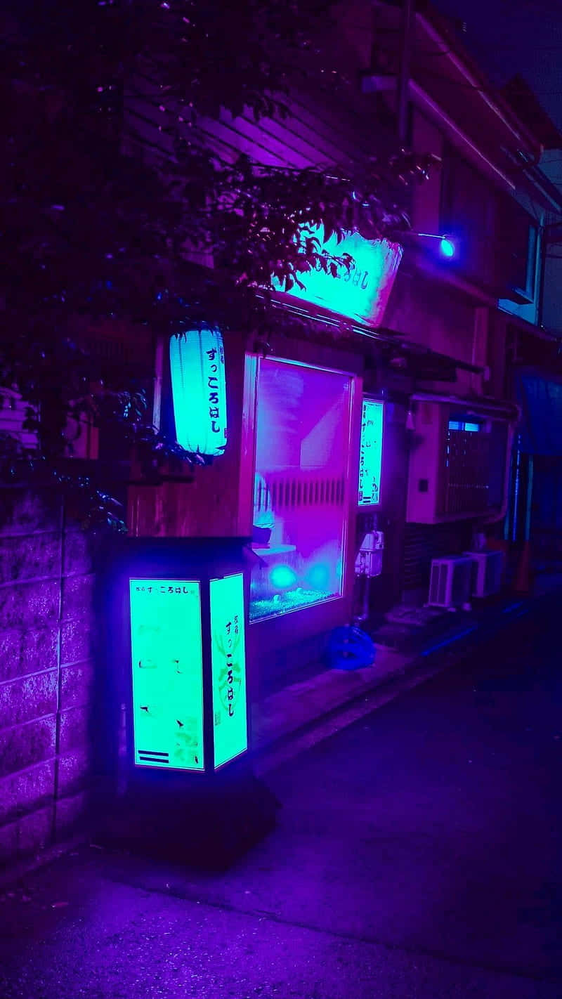 在紫藍交融中尋找內心平靜 壁紙 — 夜晚一條霓虹燈照亮的小巷，有發光的綠色自動售貨機和紫色環境燈光，在磚牆和樹木上投下陰影。