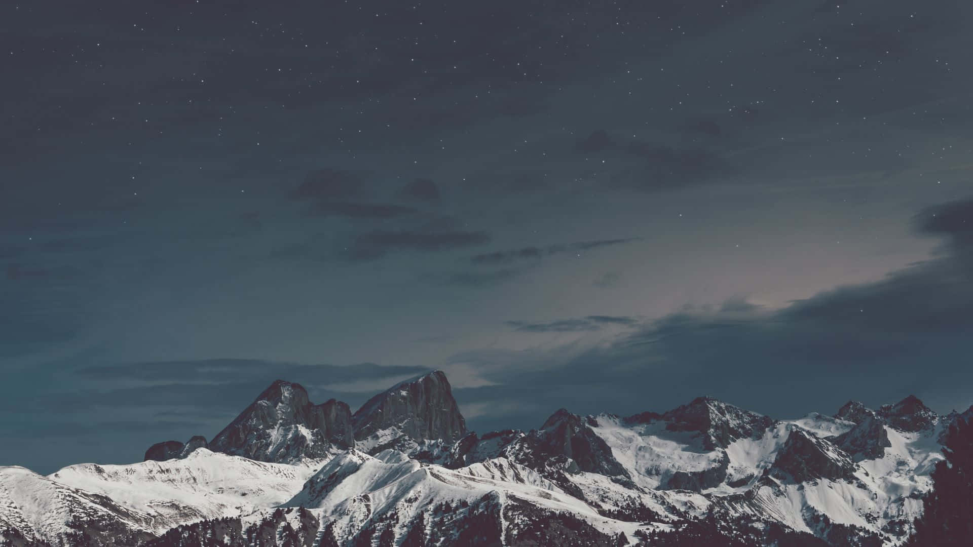 在繁星點綴的夜空下感受自然的寧靜 壁紙 — 白雪覆蓋的山峰在繁星點點的夜空下聳立，柔軟的雲朵緩緩飄過。