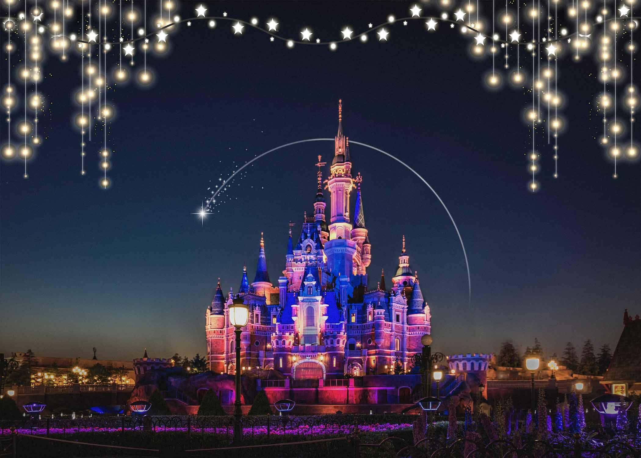 Disney Castle 桌布 壁紙 — 在繁星點點的夜空下，一座魔法城堡被紫色和粉紅色的燈光照亮，閃爍的串燈框住了整個場景。