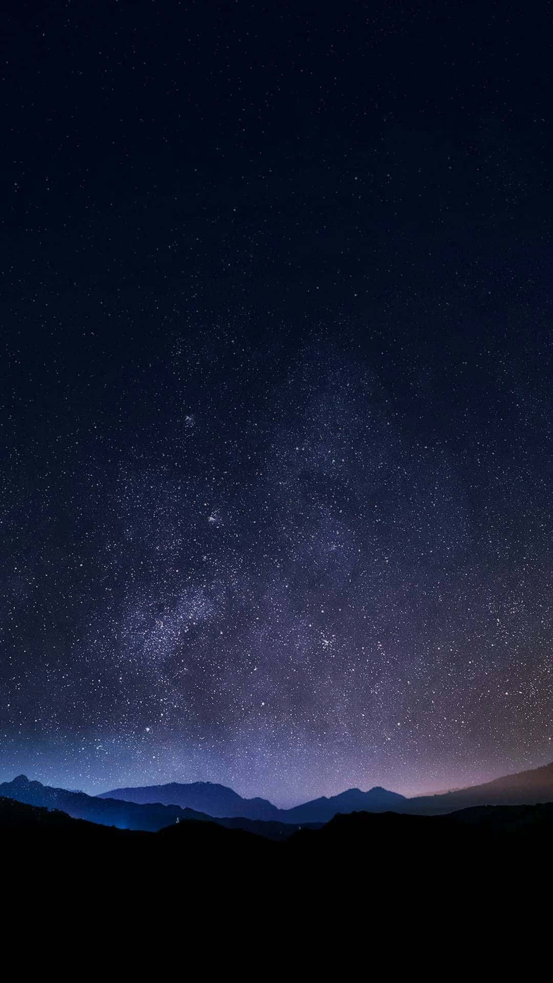 iPhone Home Screen 桌布 壁紙 — 在繁星點點的夜空下，銀河系橫跨黑暗山巒輪廓的壯麗景色。