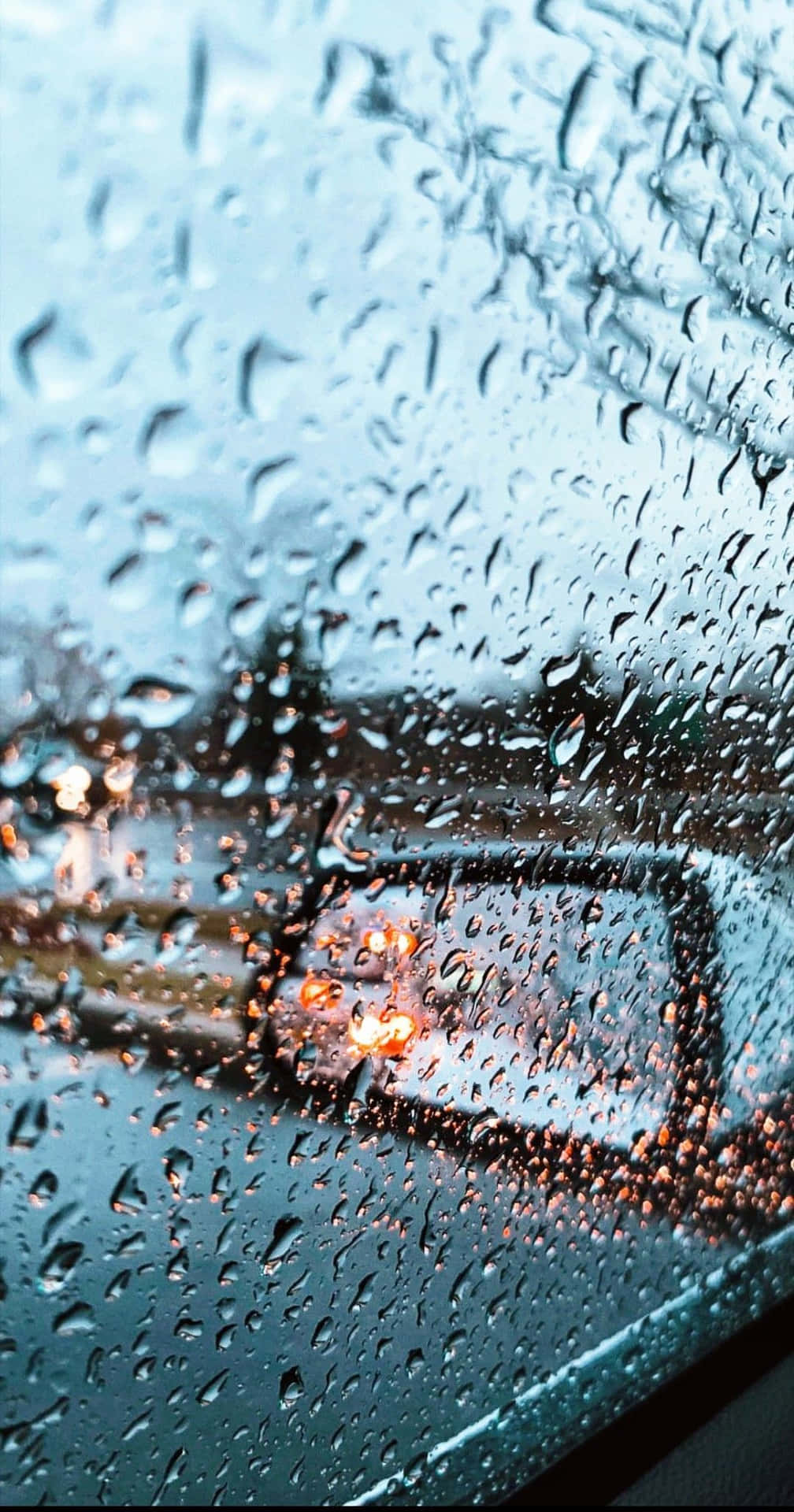 汽車車窗上的雨滴，背景中模糊的城市燈光閃爍。